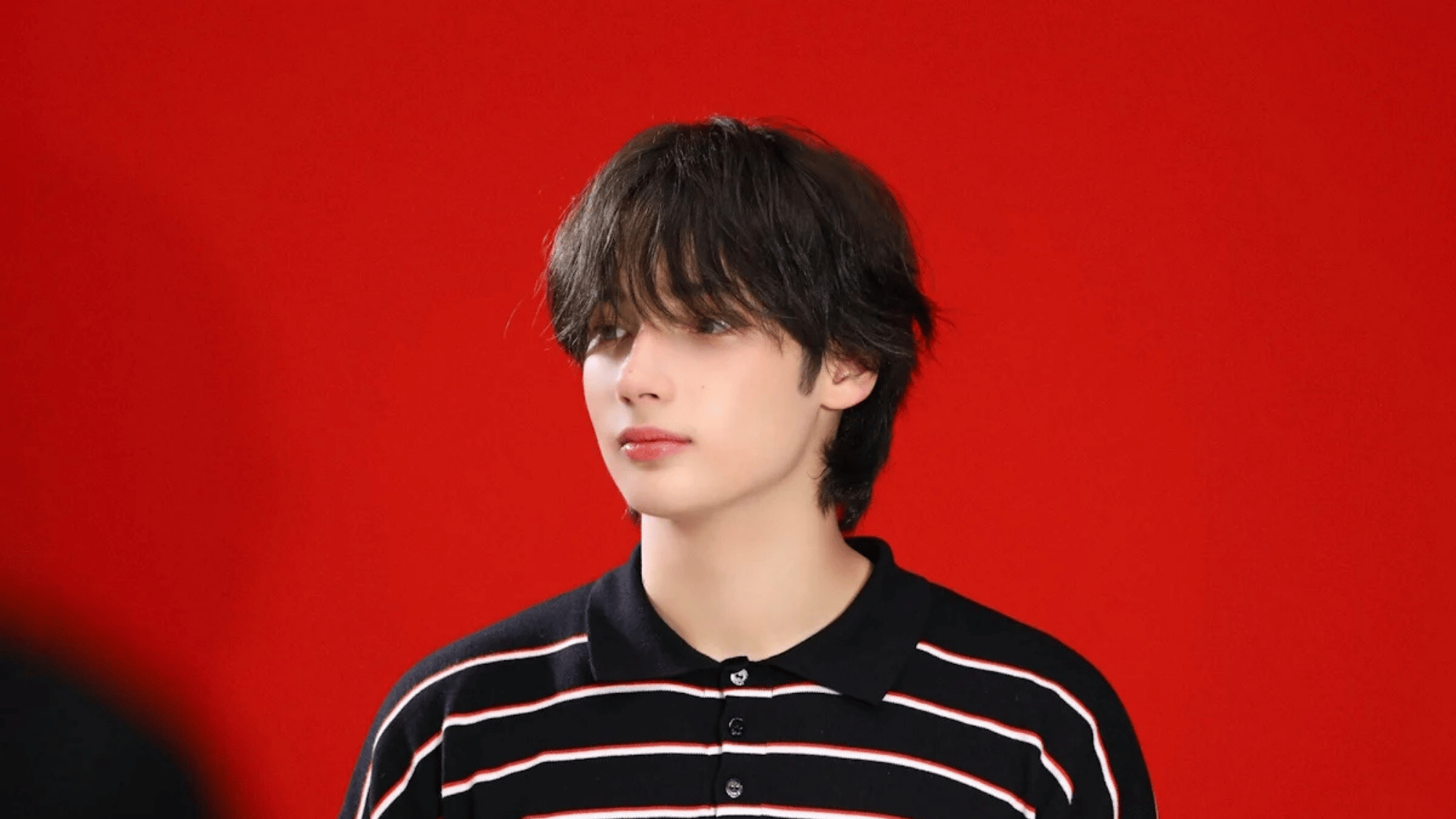 a man posing in front of a red backdrop during a studio photoshoot