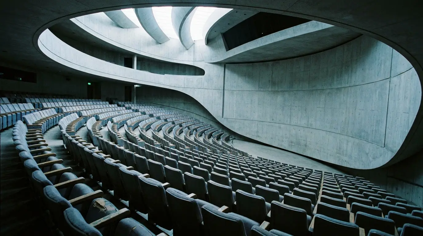 Curved modern auditorium with empty tiered seating and concrete walls