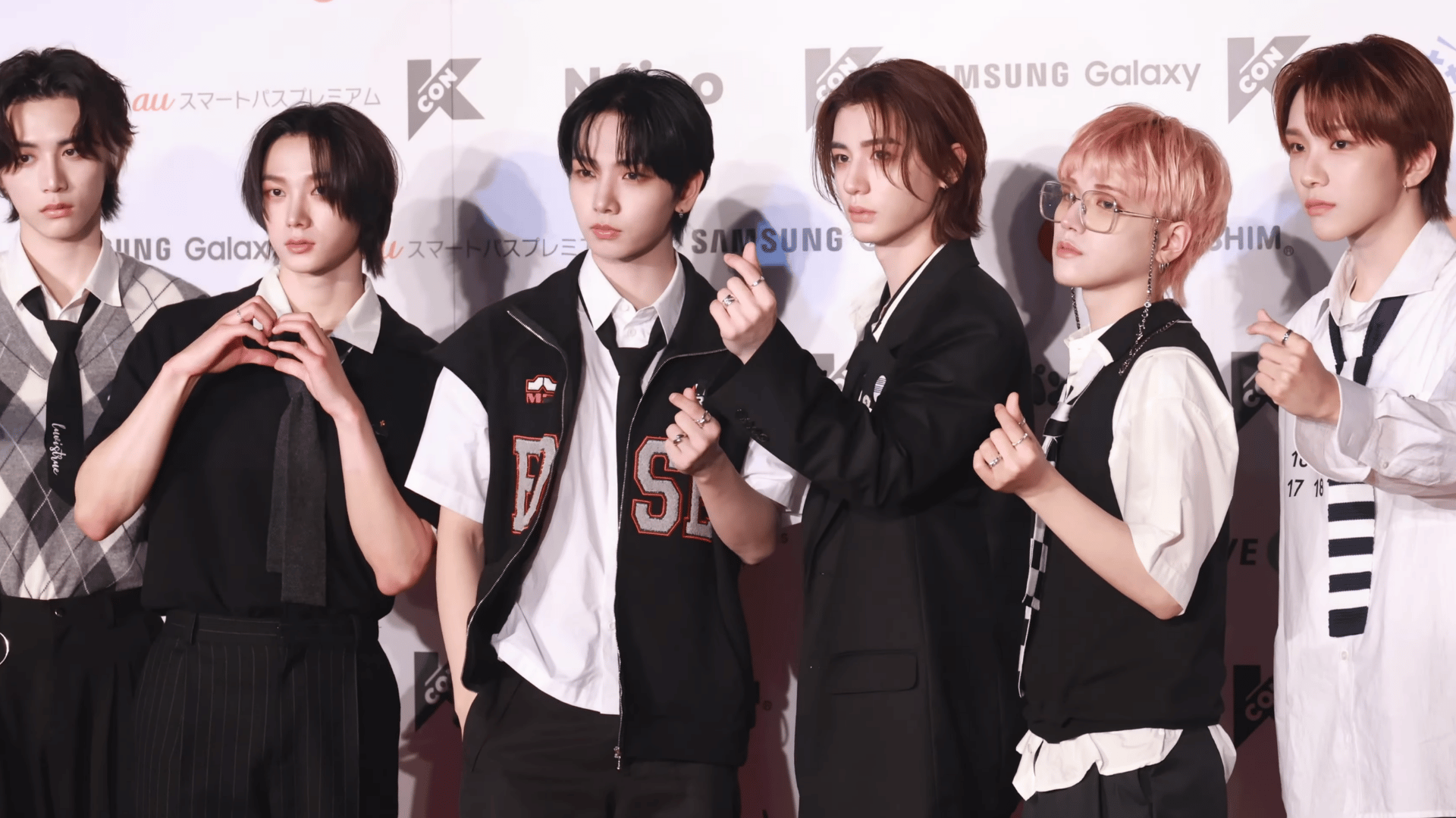 BOYNEXTDOOR members posing together at a KCON press event in coordinated outfits.