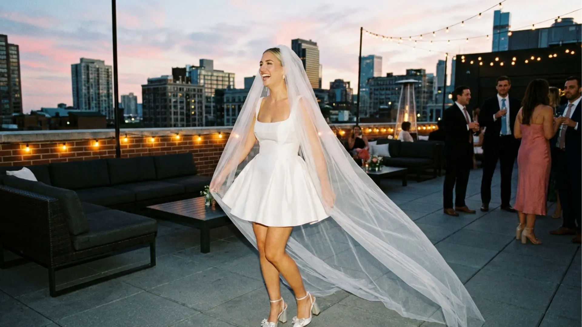Bride in a modern mini wedding dress dancing at a city rooftop reception