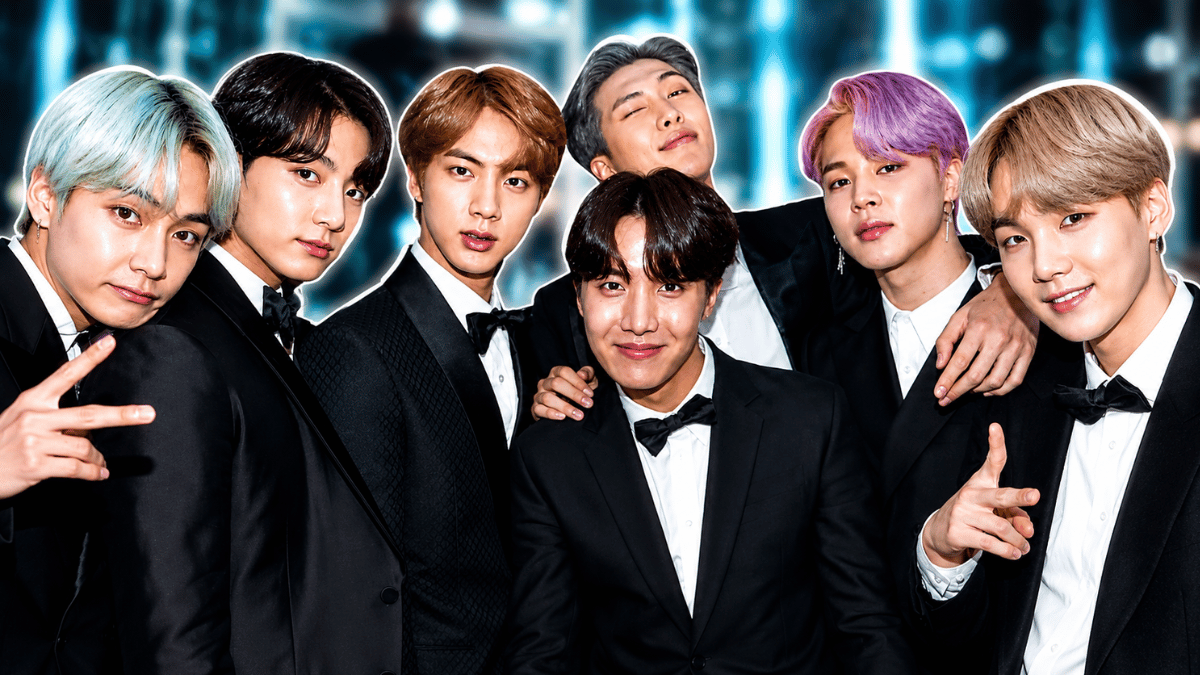 BTS members posing in black tuxedos against a glowing blue backdrop