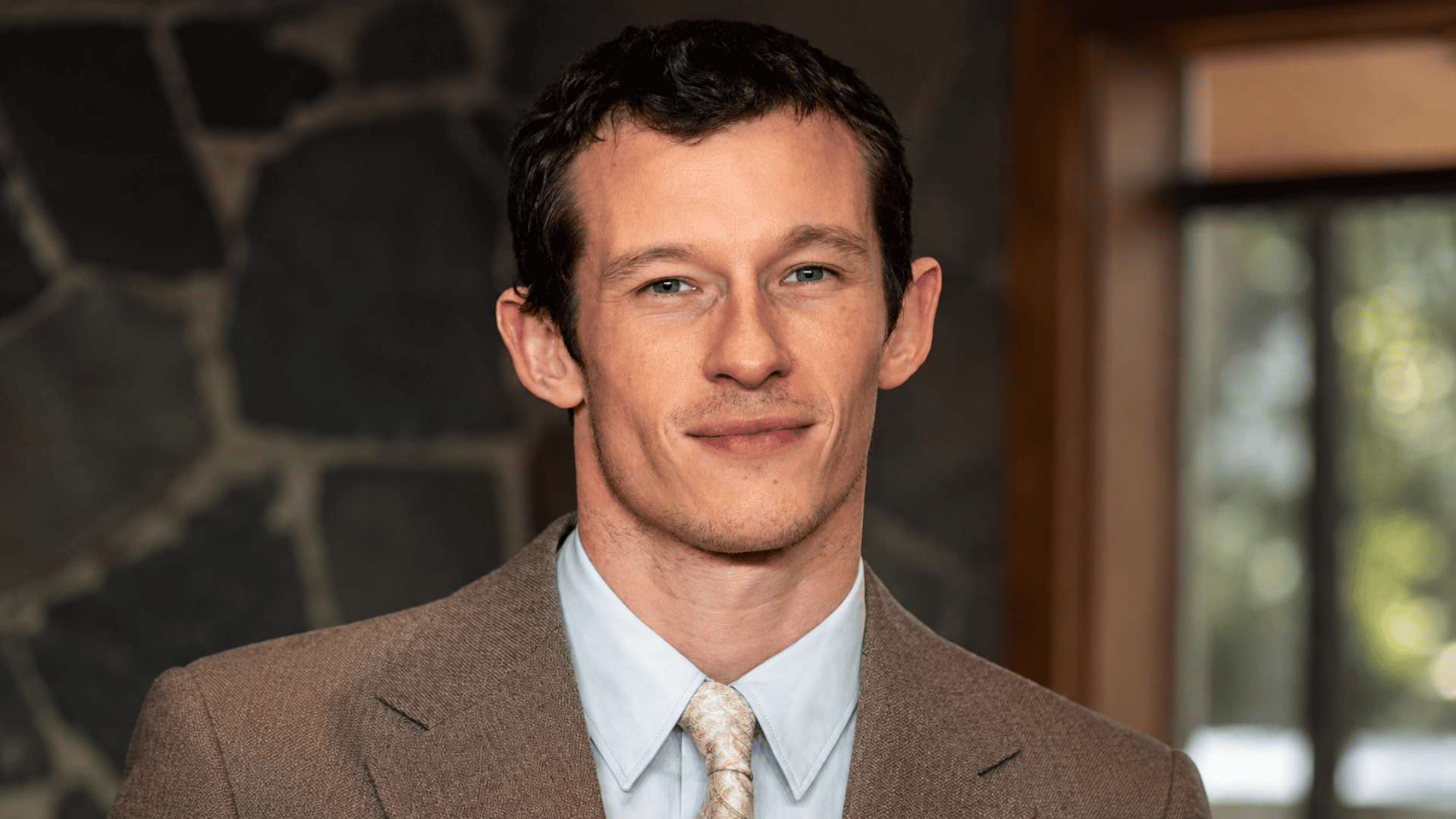 ortrait of Callum Turner with a modern blurred indoor background