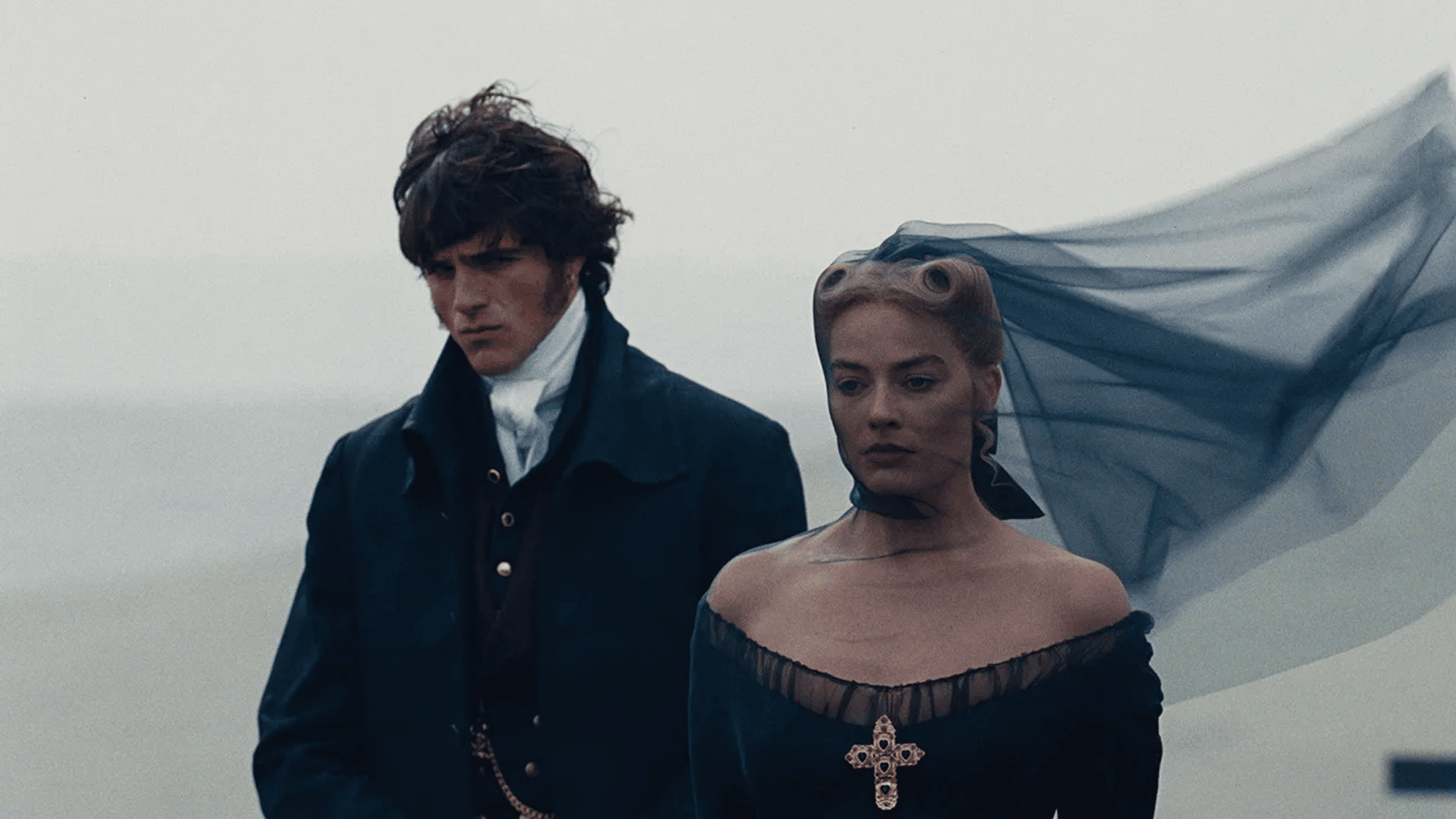 Period drama pair walk on misty moors with dark veil blowing behind them