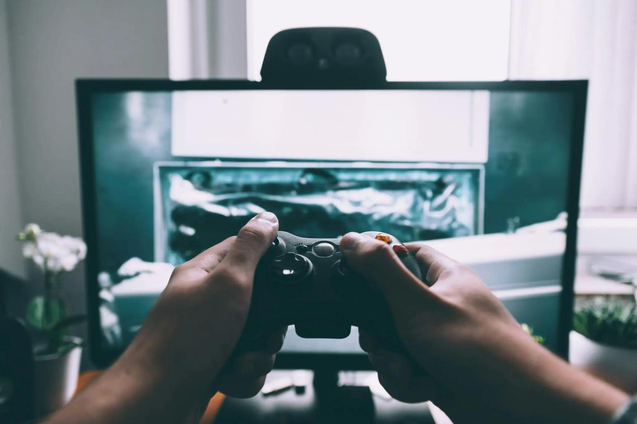 Hands holding a game controller with a television screen in the background