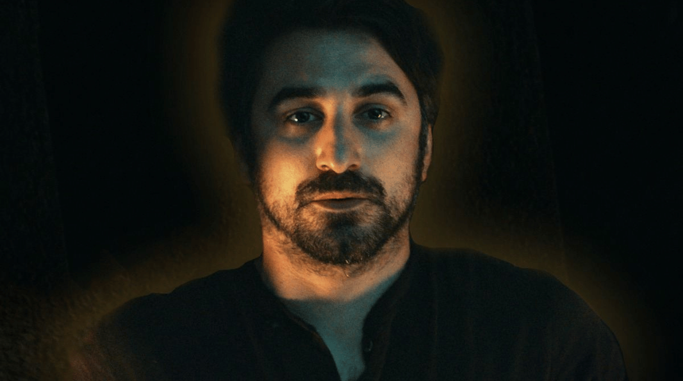 George Wilkins lit by warm light in a dark room.