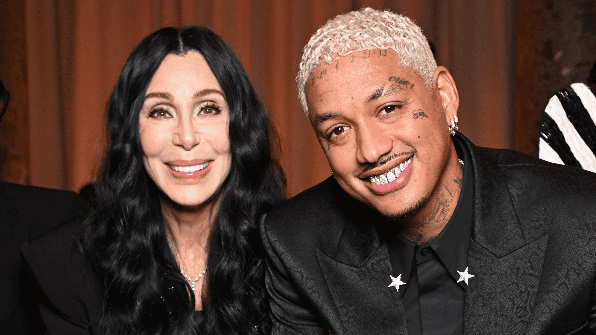 Singer and partner smiling together at an indoor celebrity event