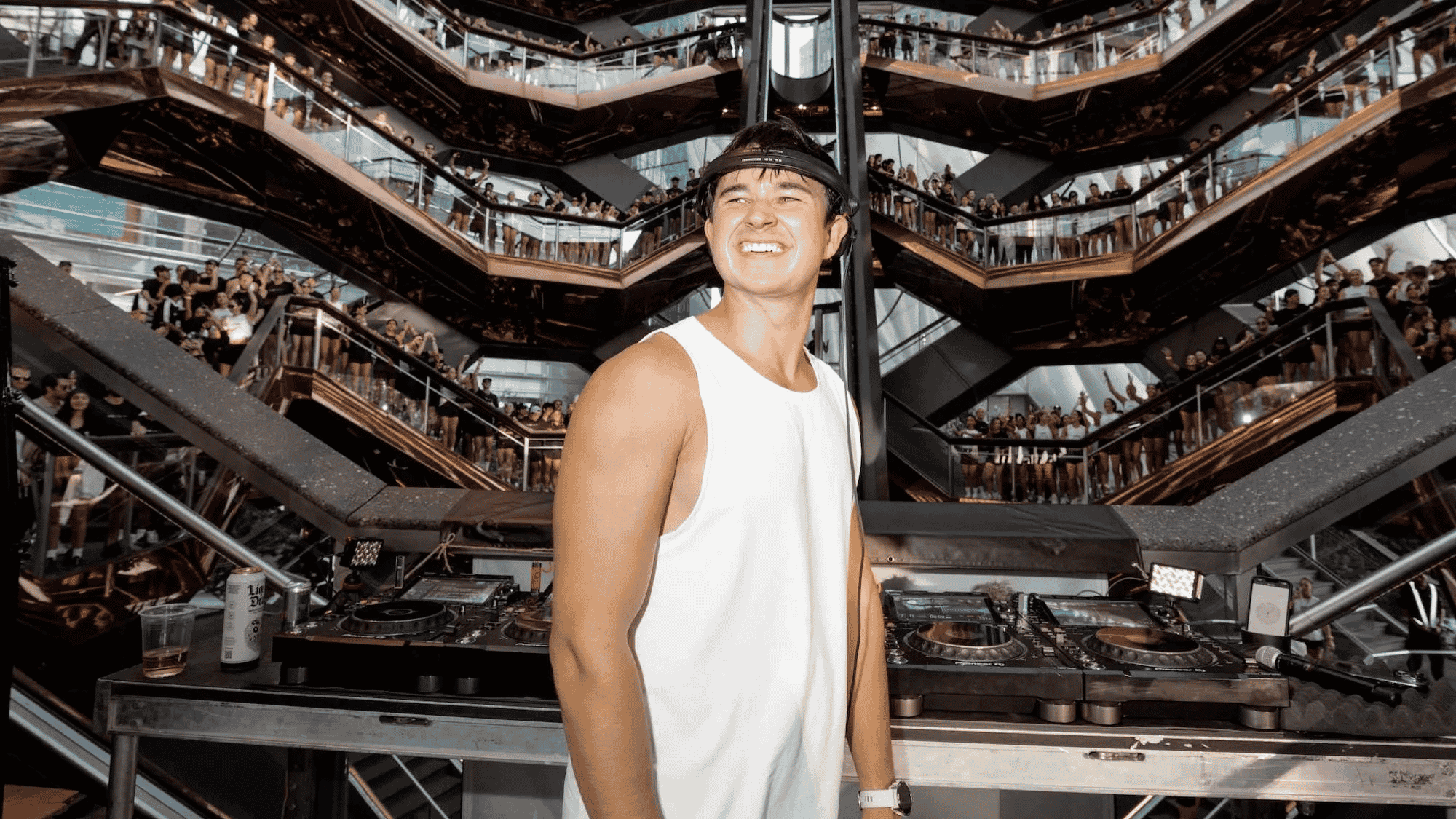 miling DJ behind the decks as a crowd fills a multi-level venue