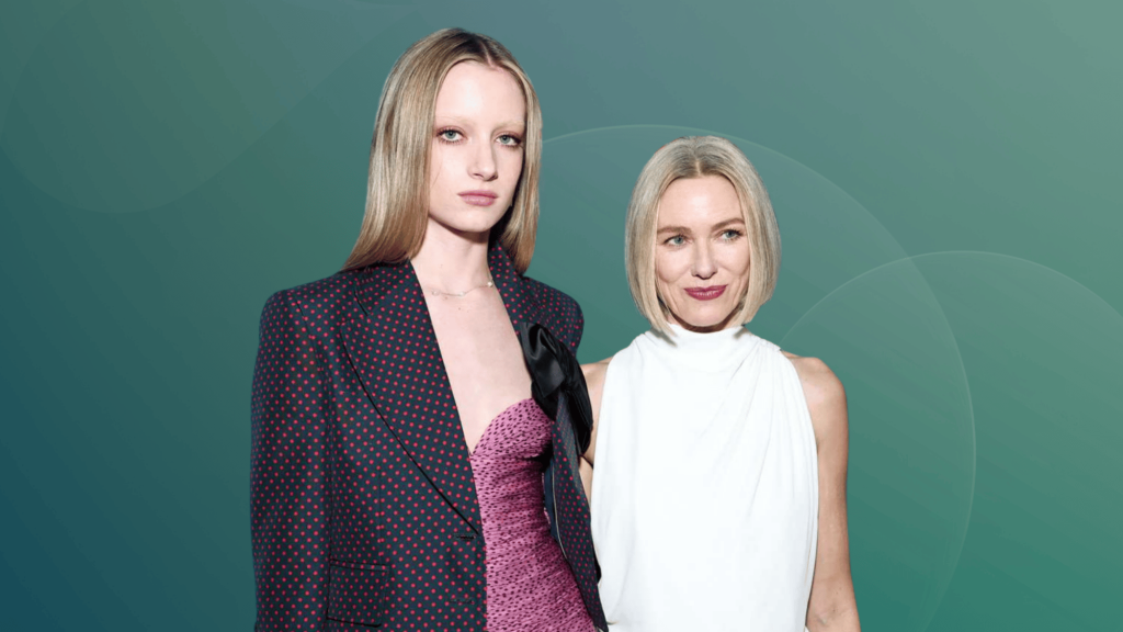 Kai Schreiber standing beside Naomi Watts at a public event, wearing elegant outfits against a teal backdrop.