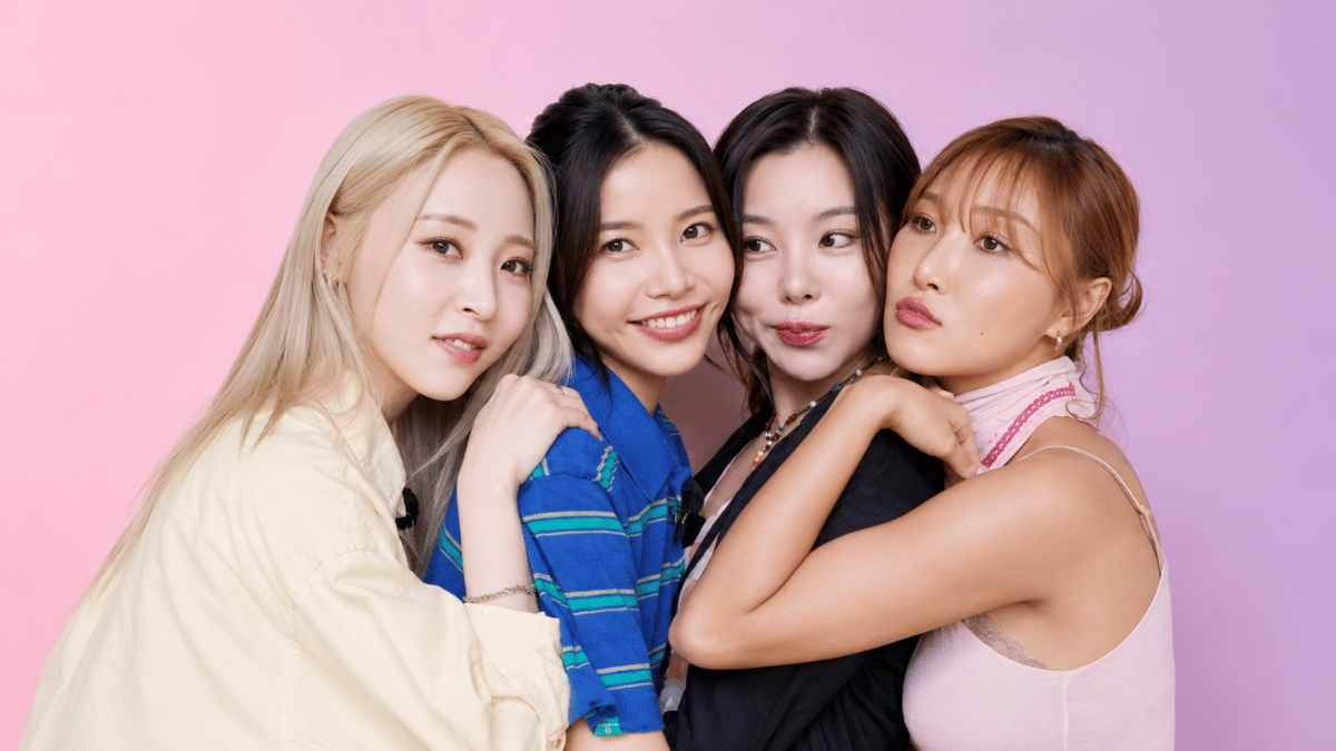 mamamoo members posing in colorful outfits on a pastel pink background