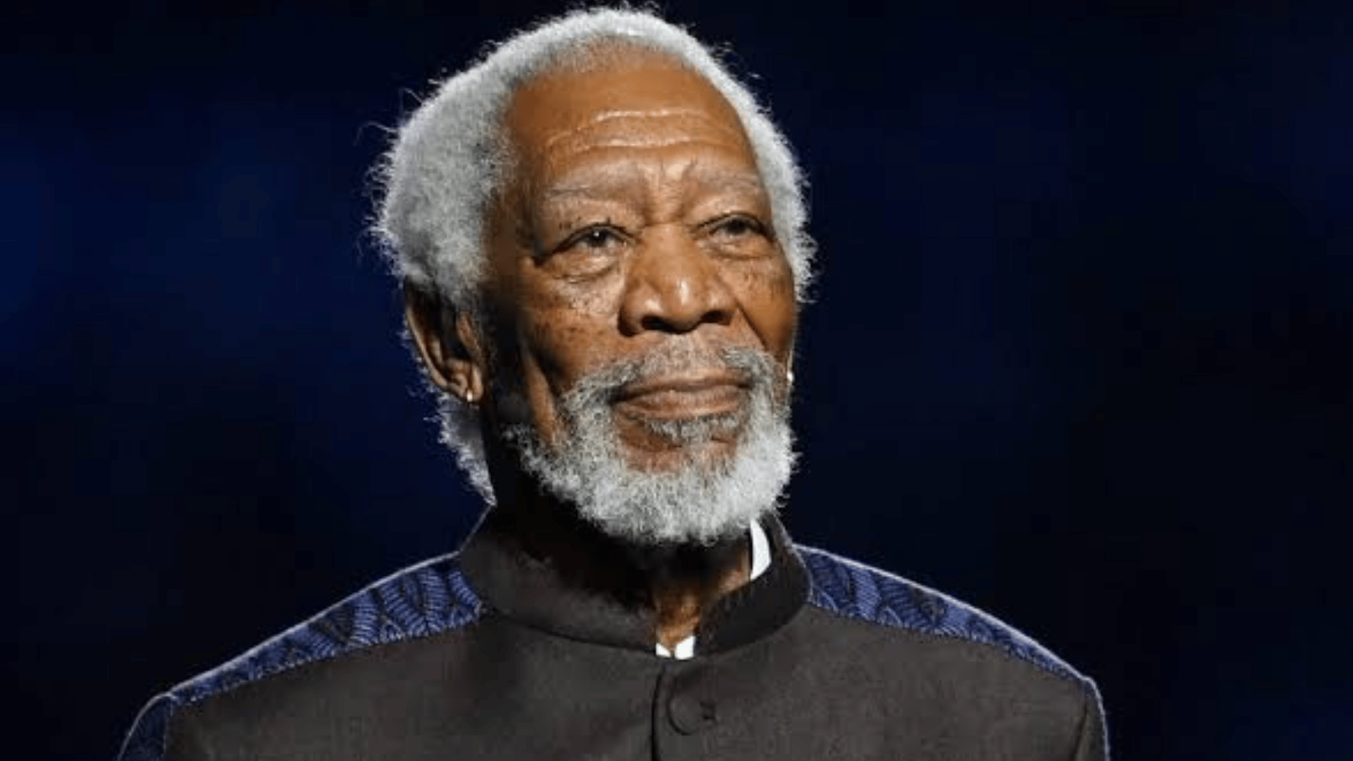 Morgan Freeman standing on stage wearing a dark outfit during a public appearance.