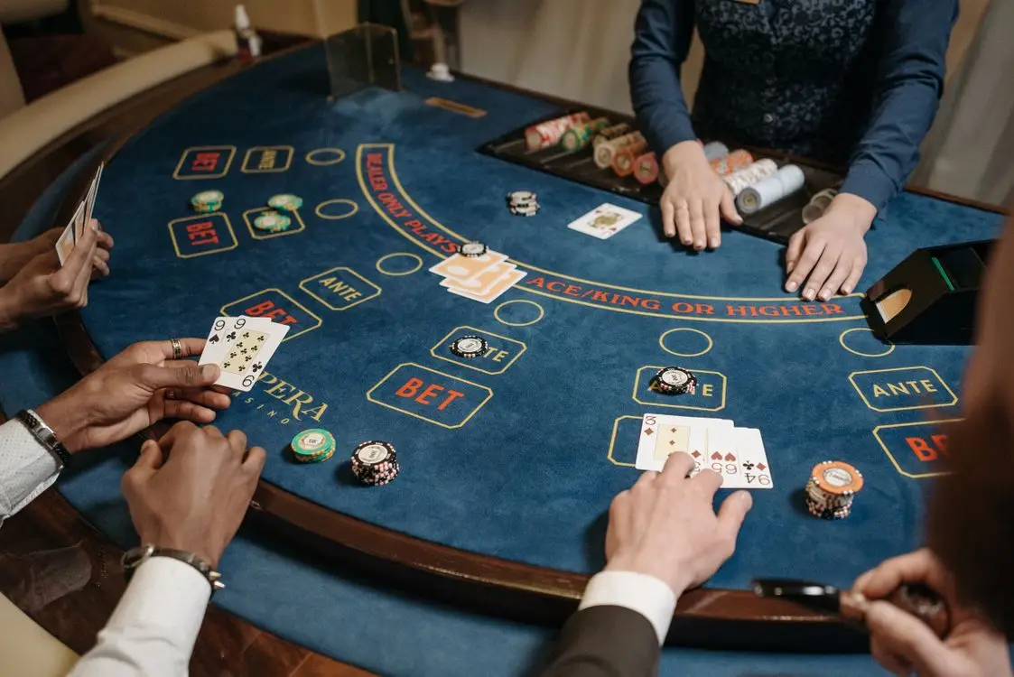 People playing poker at a casino table with blue felt and poker chips