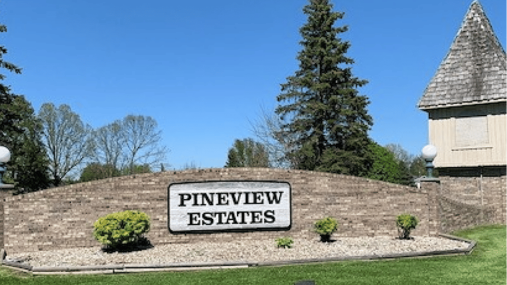 pineview estates entrance sign showing the manufactured home community exterior with landscaping and clear blue sky background