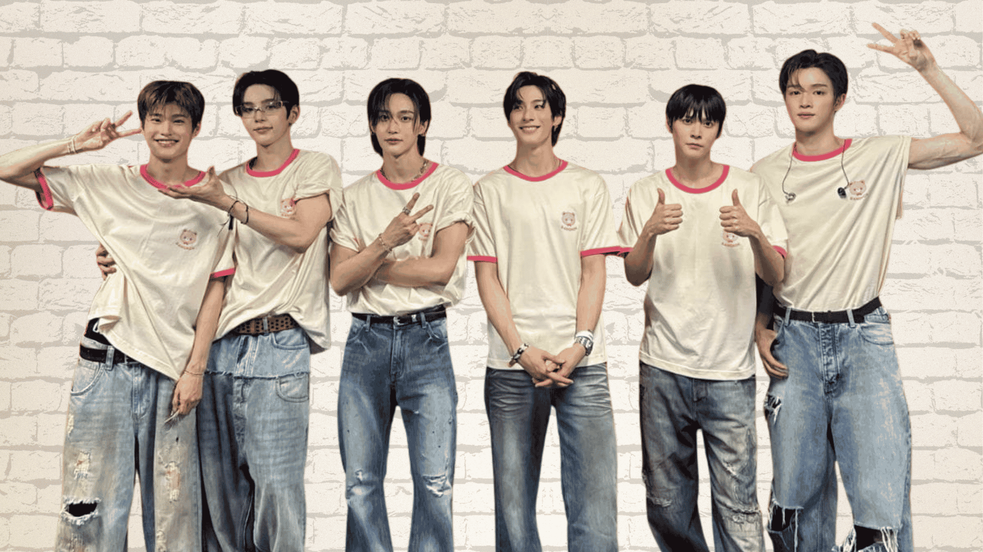 RIIZE members posing together in matching white T-shirts and jeans, smiling and making hand gestures against a brick wall backdrop.