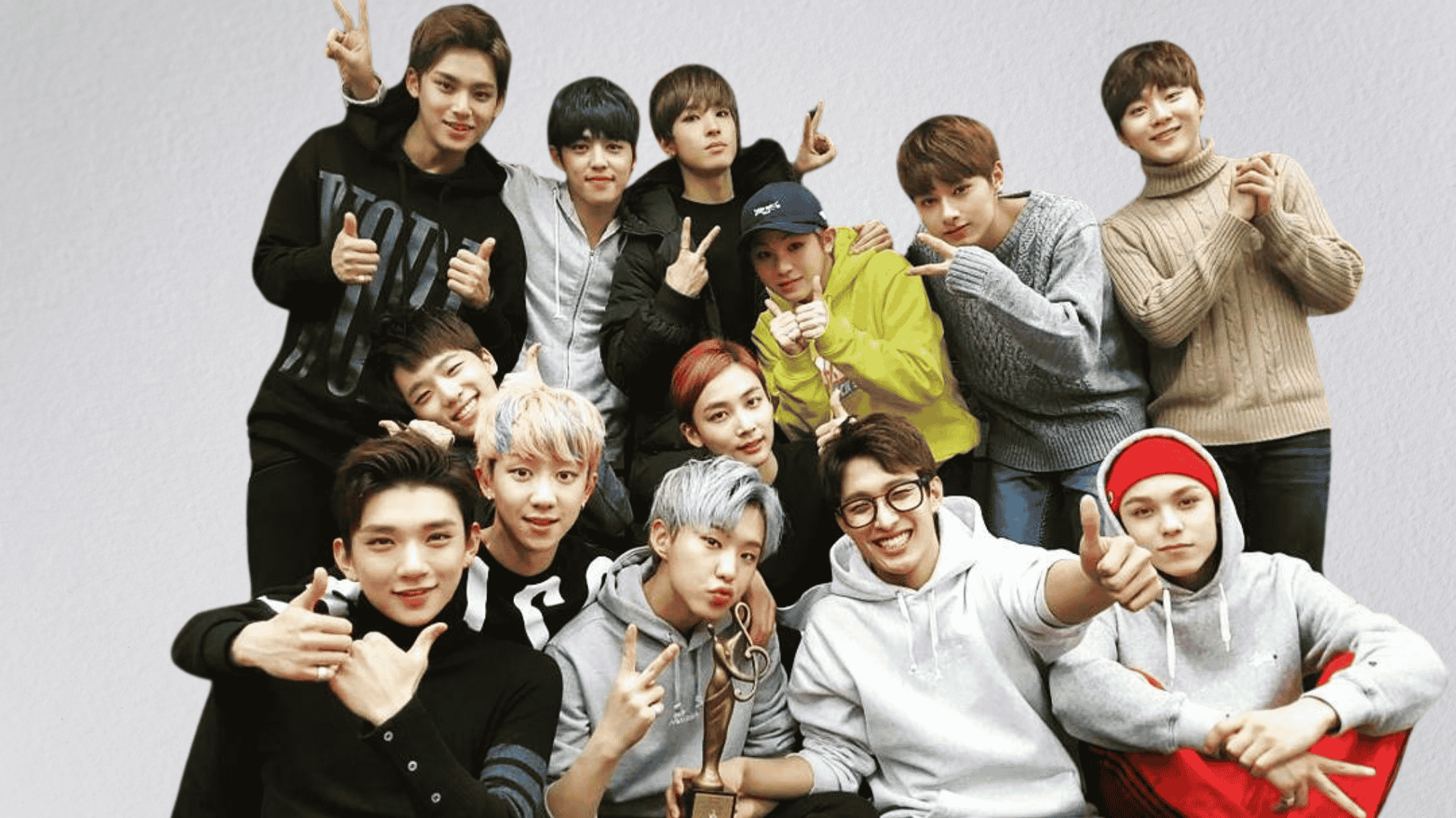 SEVENTEEN members posing together in casual outfits, smiling and holding an award during a group celebration photo.