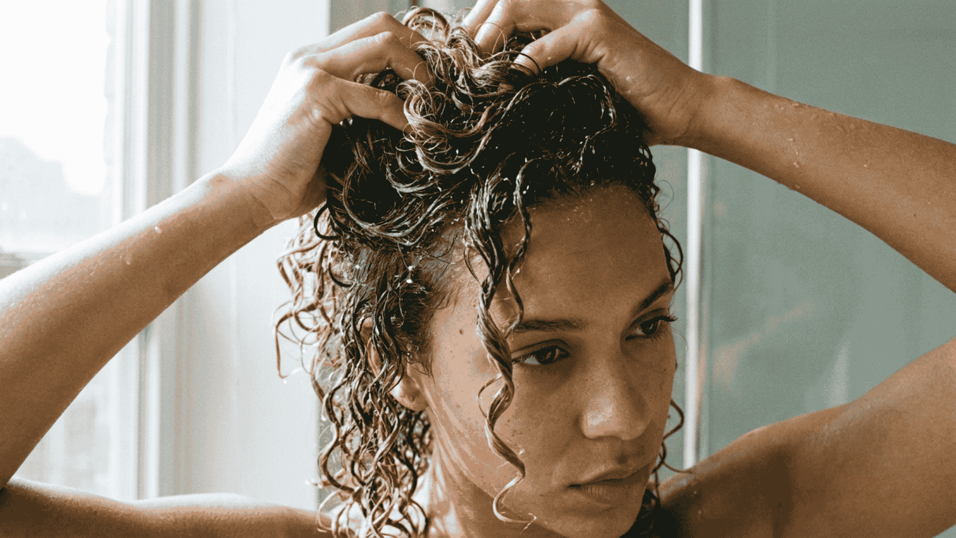 woman scrunching and finger coiling wet hair to shape defined curls