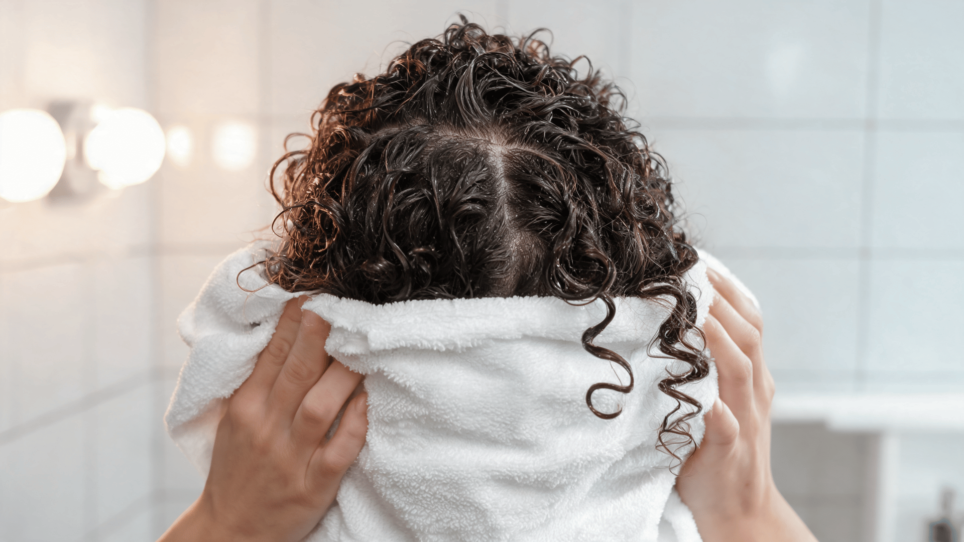 soft microfiber towel pressing curly ends upward to remove extra water without rubbing the hair