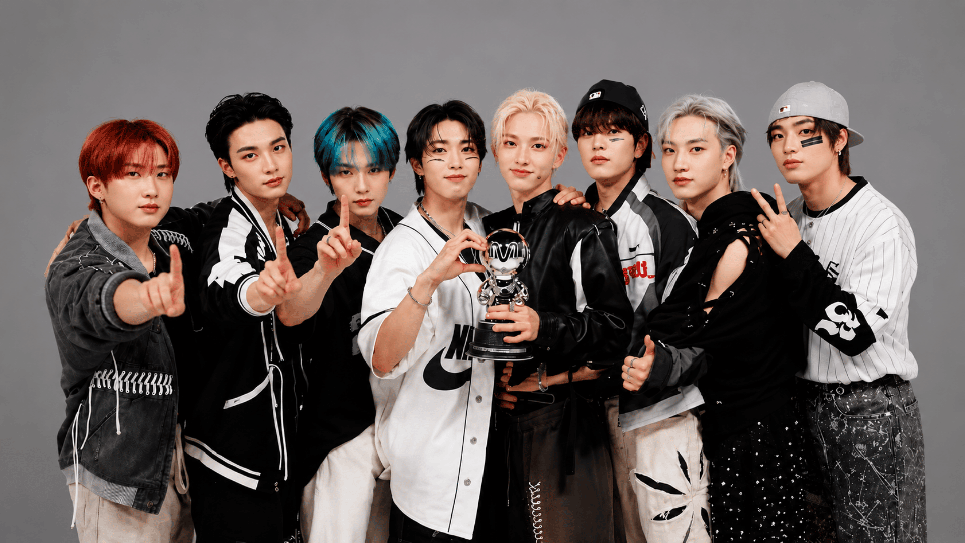 Stray Kids members pose with a trophy against a plain gray studio background