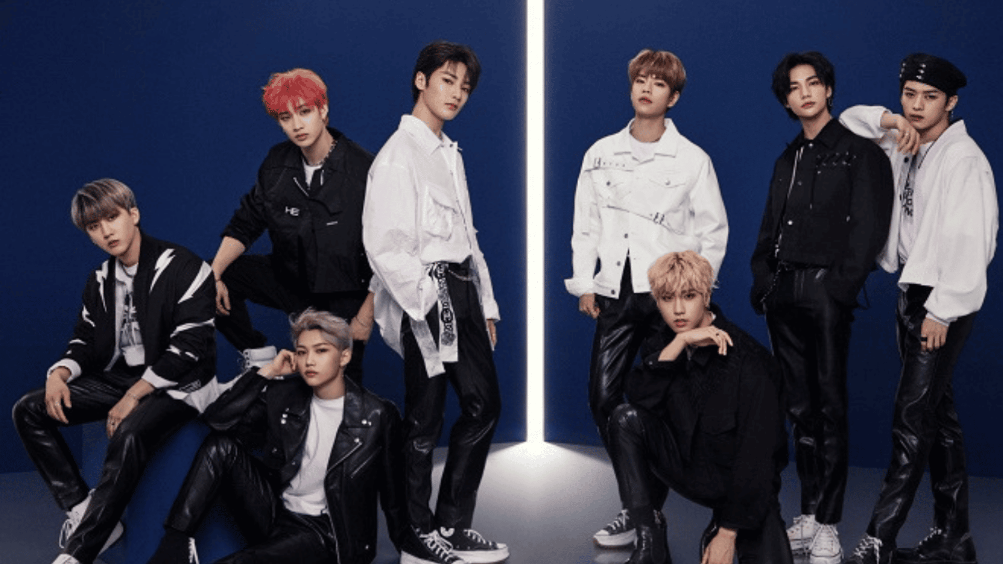 Stray Kids members posing together in black and white outfits during an official group photoshoot.