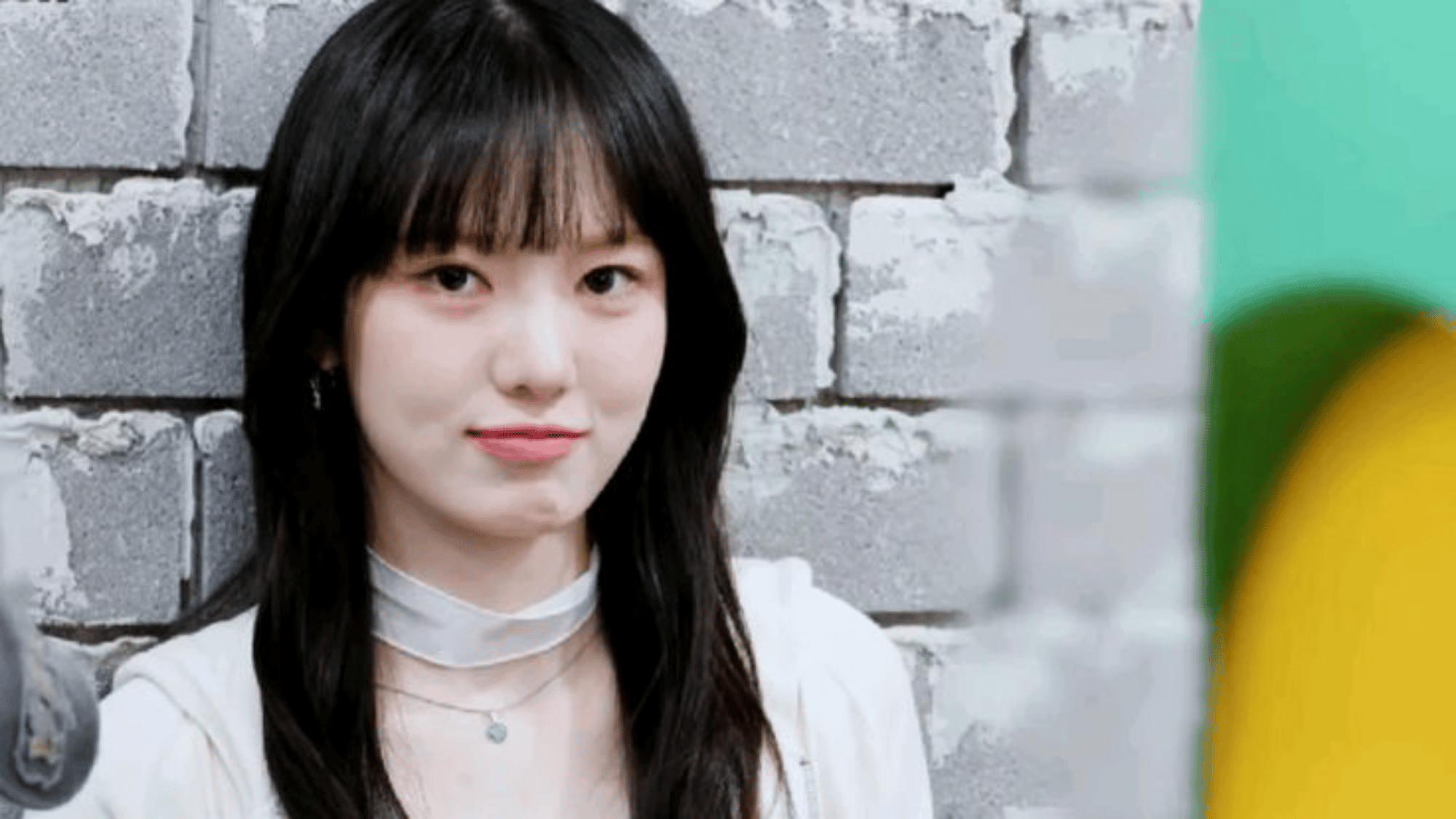 KiiiKiii member Sui smiling with bangs and a sheer choker necklace