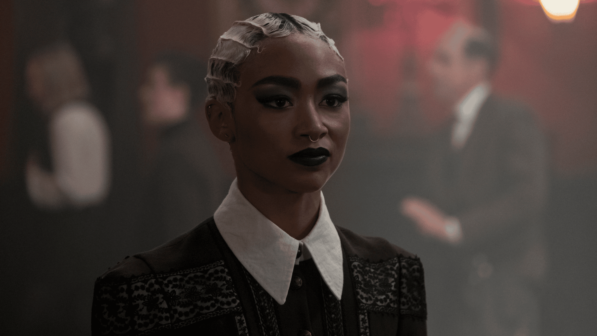 Woman with short blonde hair standing in a smoky formal room