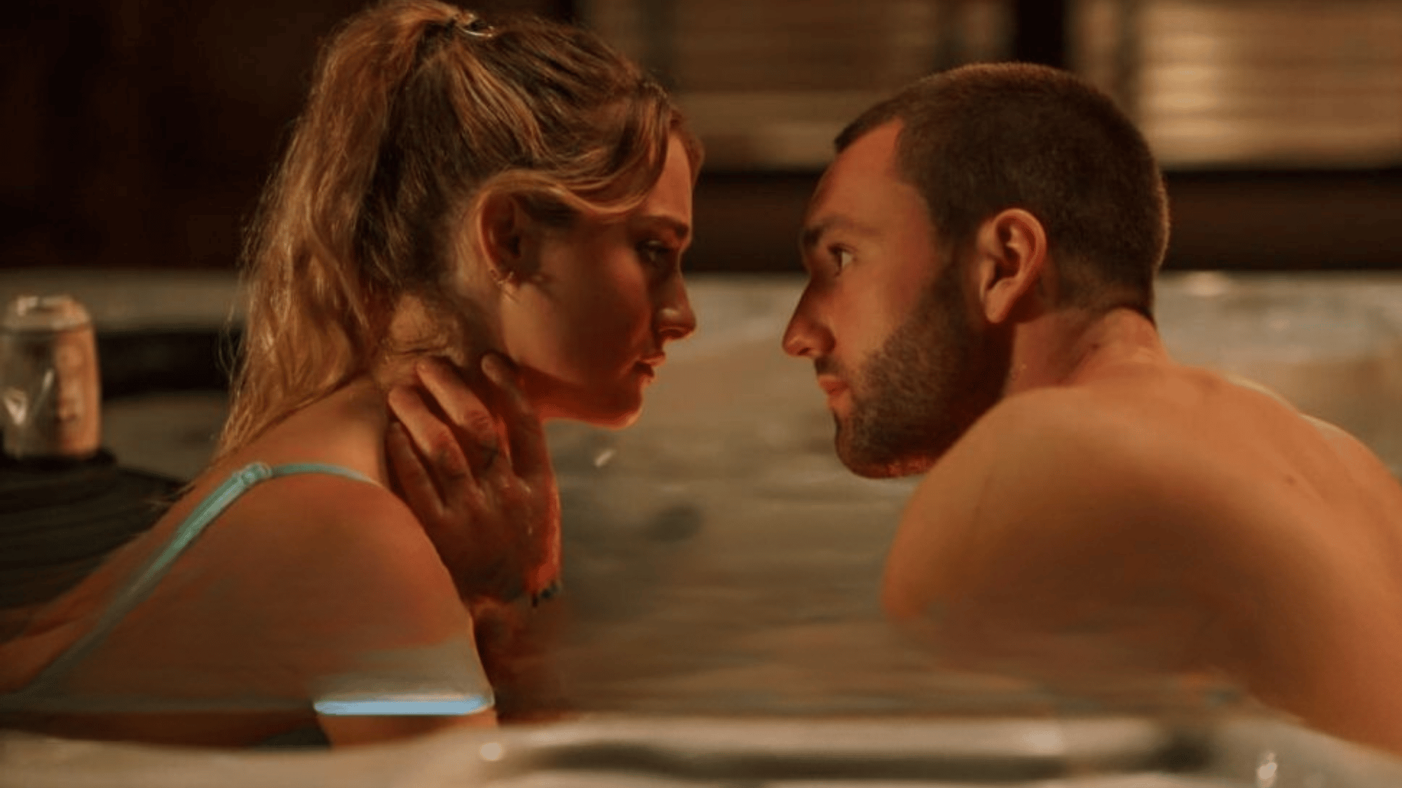 Stephen and Lucy stare intensely at each other in a warm hot tub scene.