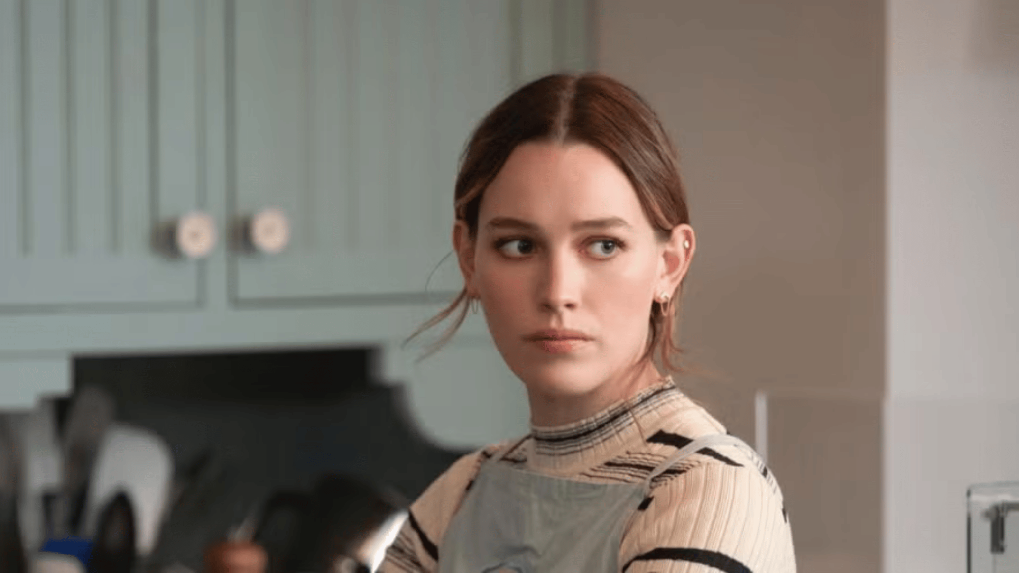 Red-haired woman looking sideways in a modern kitchen setting