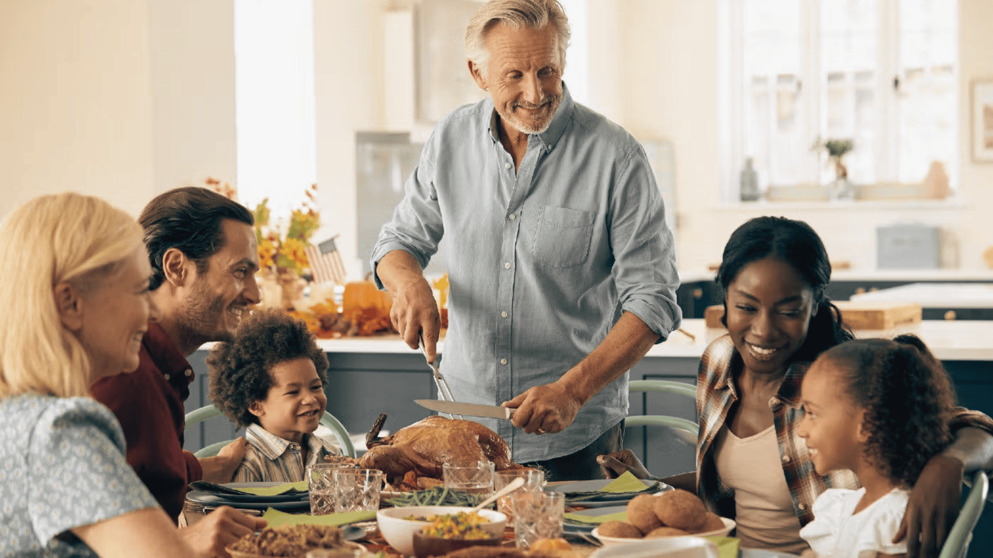 white man cutting up a turkey for a thanksgiving celebration in a warm and mixed family environment