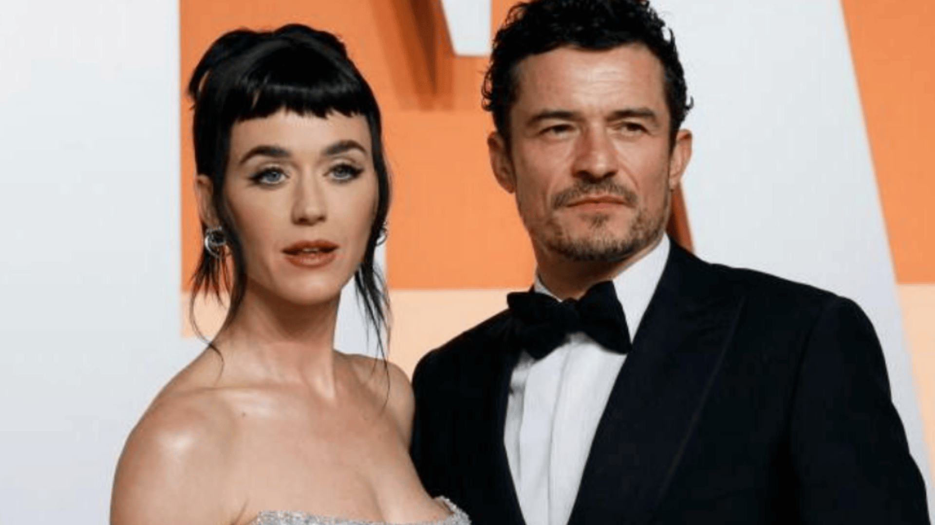 Katy Perry and Orlando Bloom posing together at a red carpet event in formal attire