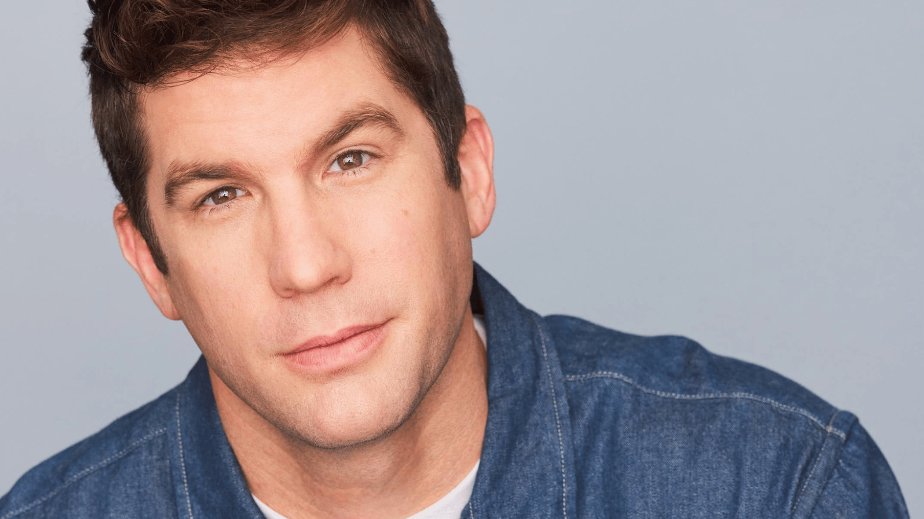 alex bonifer wearing a blue sweatshirt and is posing for some magazine shoot with a plain background