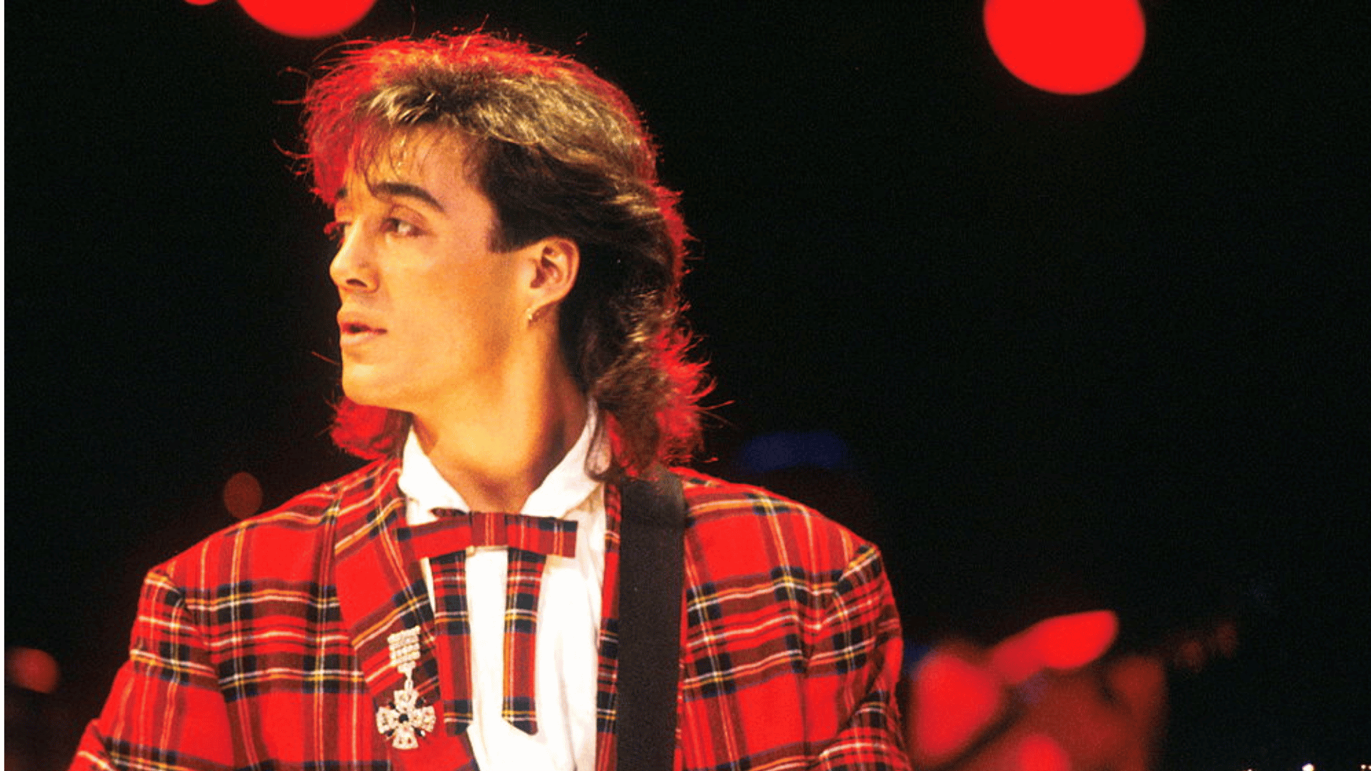 andrew ridgeley playing guitar at an event.