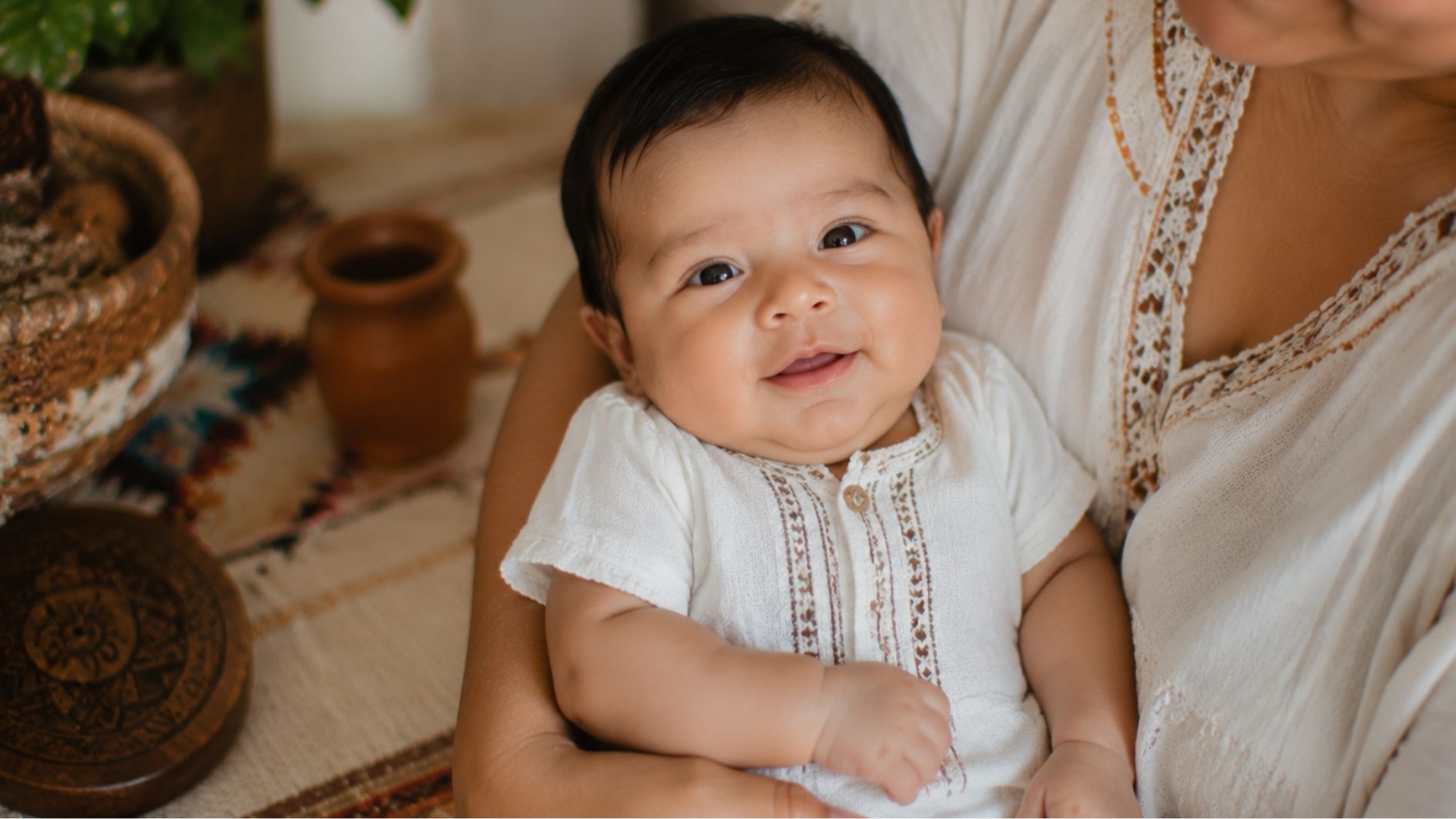 baby boy around 3 months old sitting comfortably in a parent’s arms.