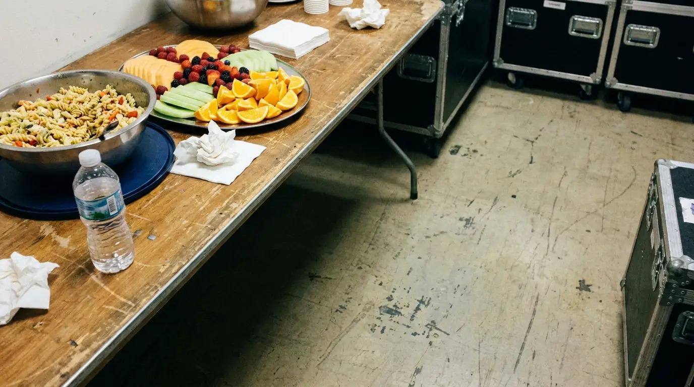 Platters of fresh fruit and pasta on a wooden table in a backstage setting