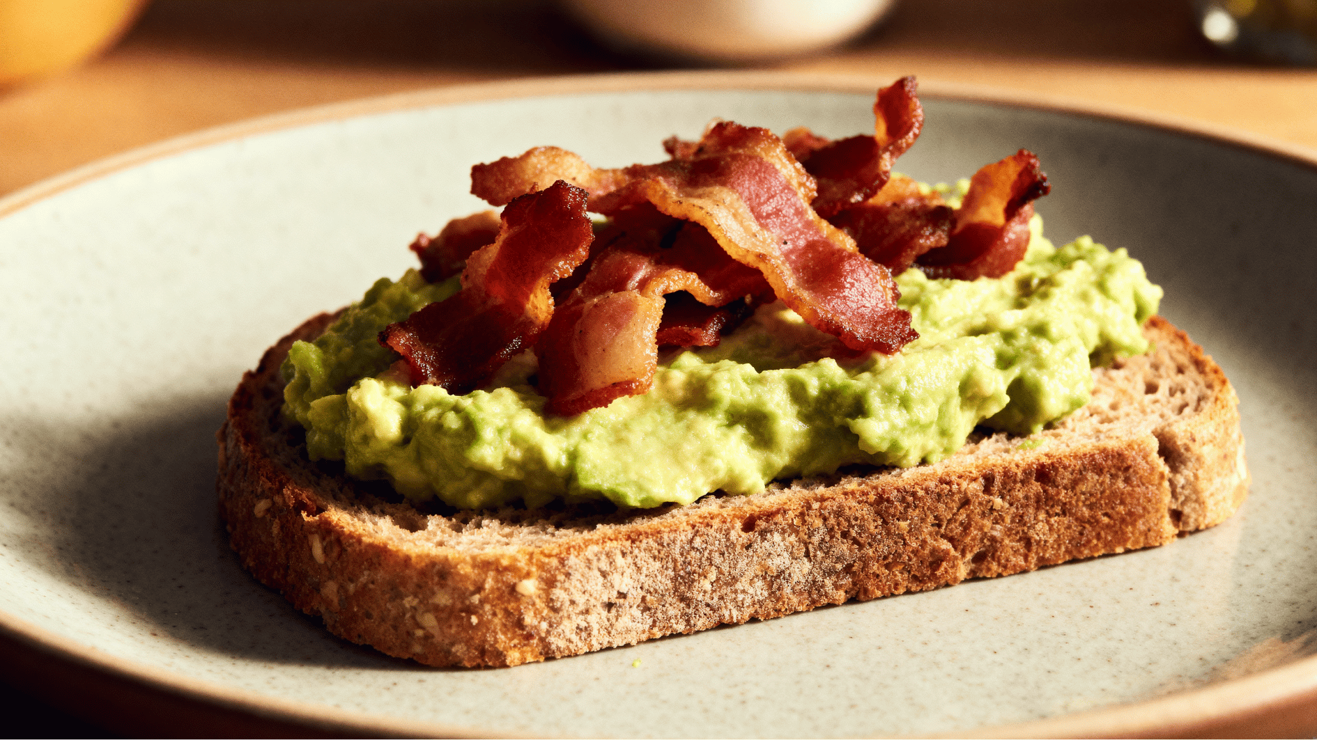 bacon avocado toast with crispy bacon pieces and creamy avocado spread on whole grain bread breakfast plate