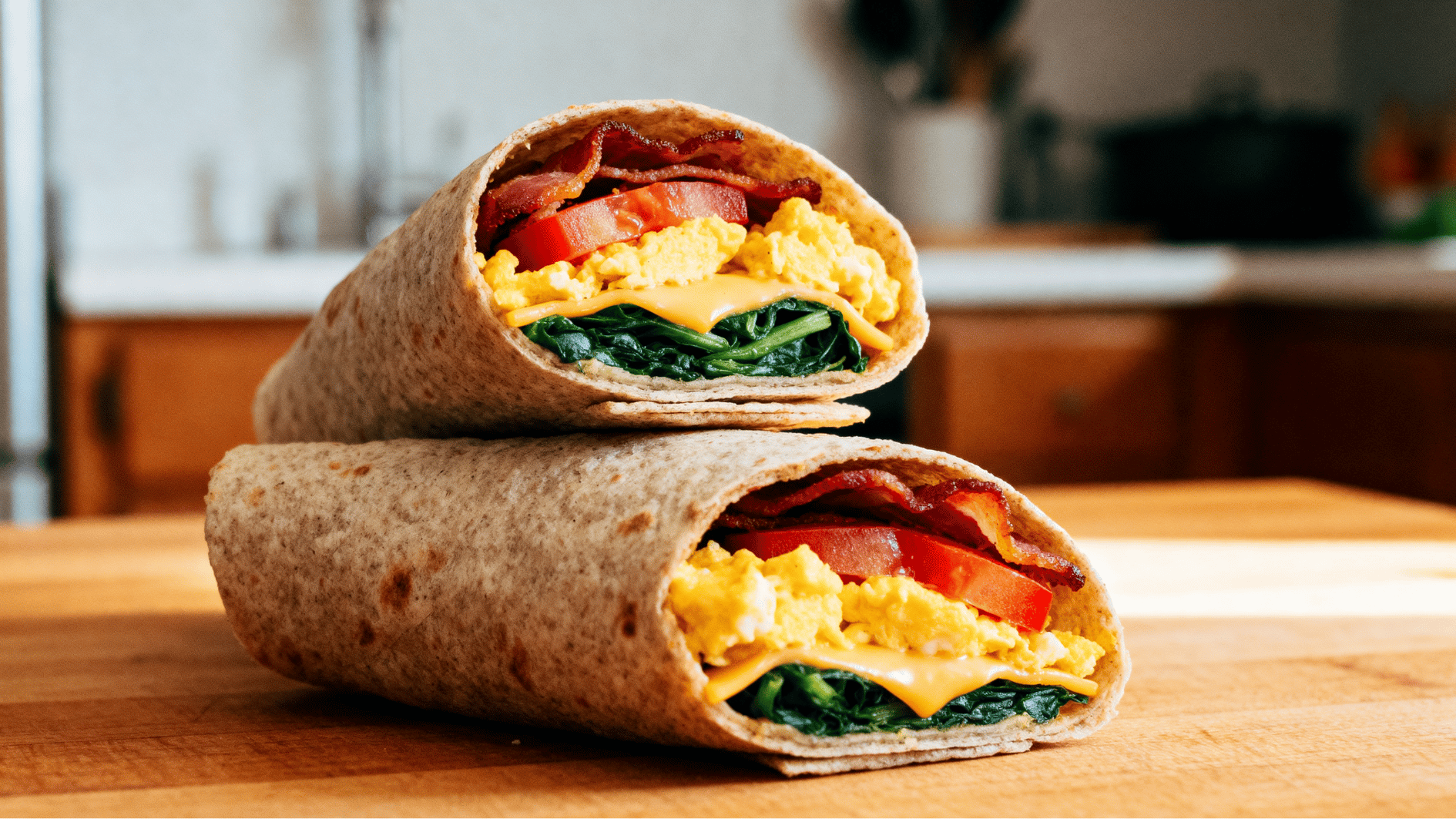 bacon and egg breakfast wrap with scrambled eggs, vegetables, cheese, and crispy bacon filling on a kitchen table