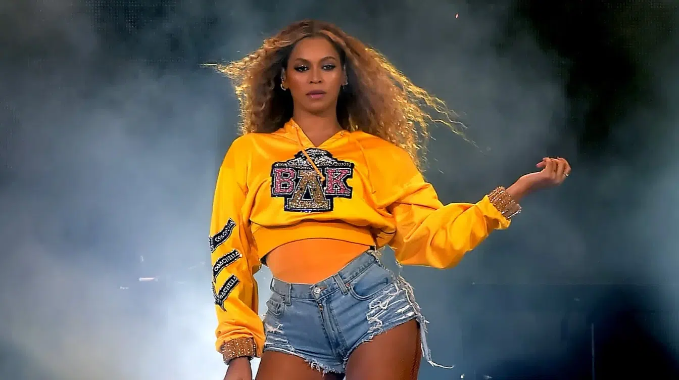 beyonce performing on stage in yellow cropped sweatshirt and denim shorts