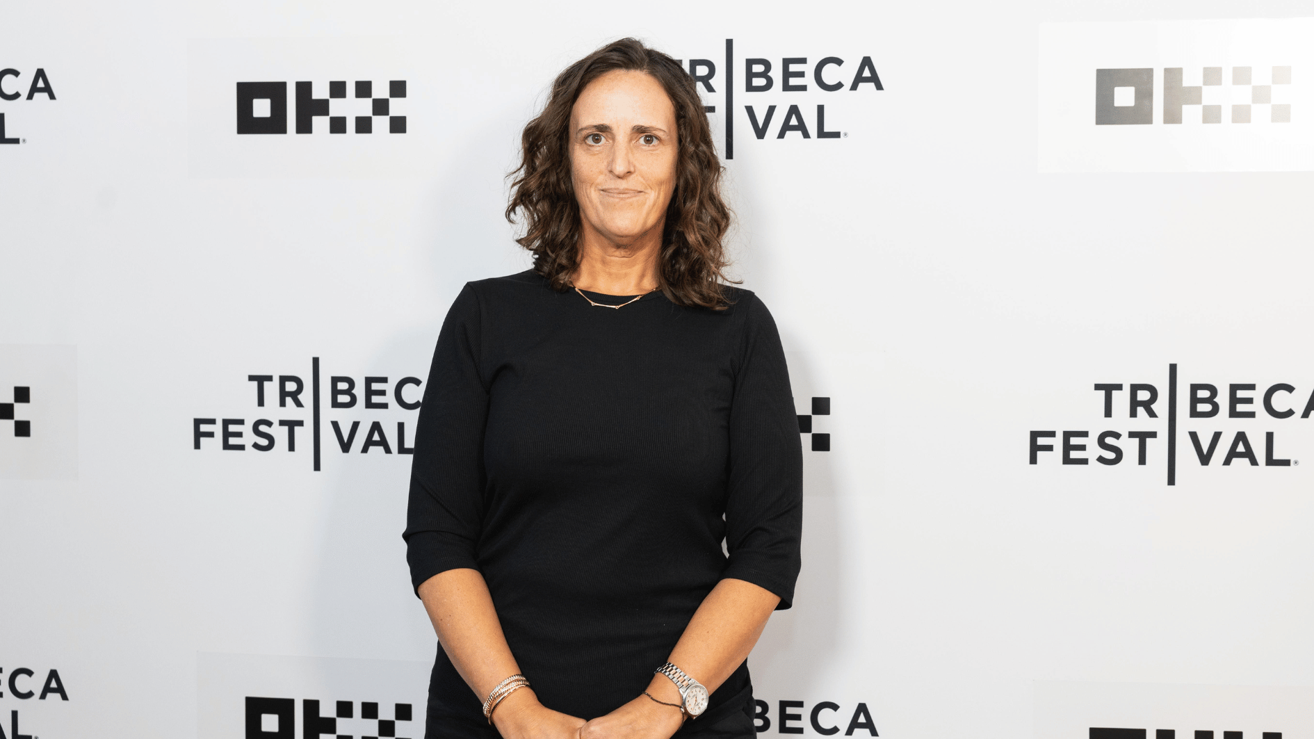 blair beeken wearing a black outfit posing at the tribeca festival in front of a branded white event backdrop