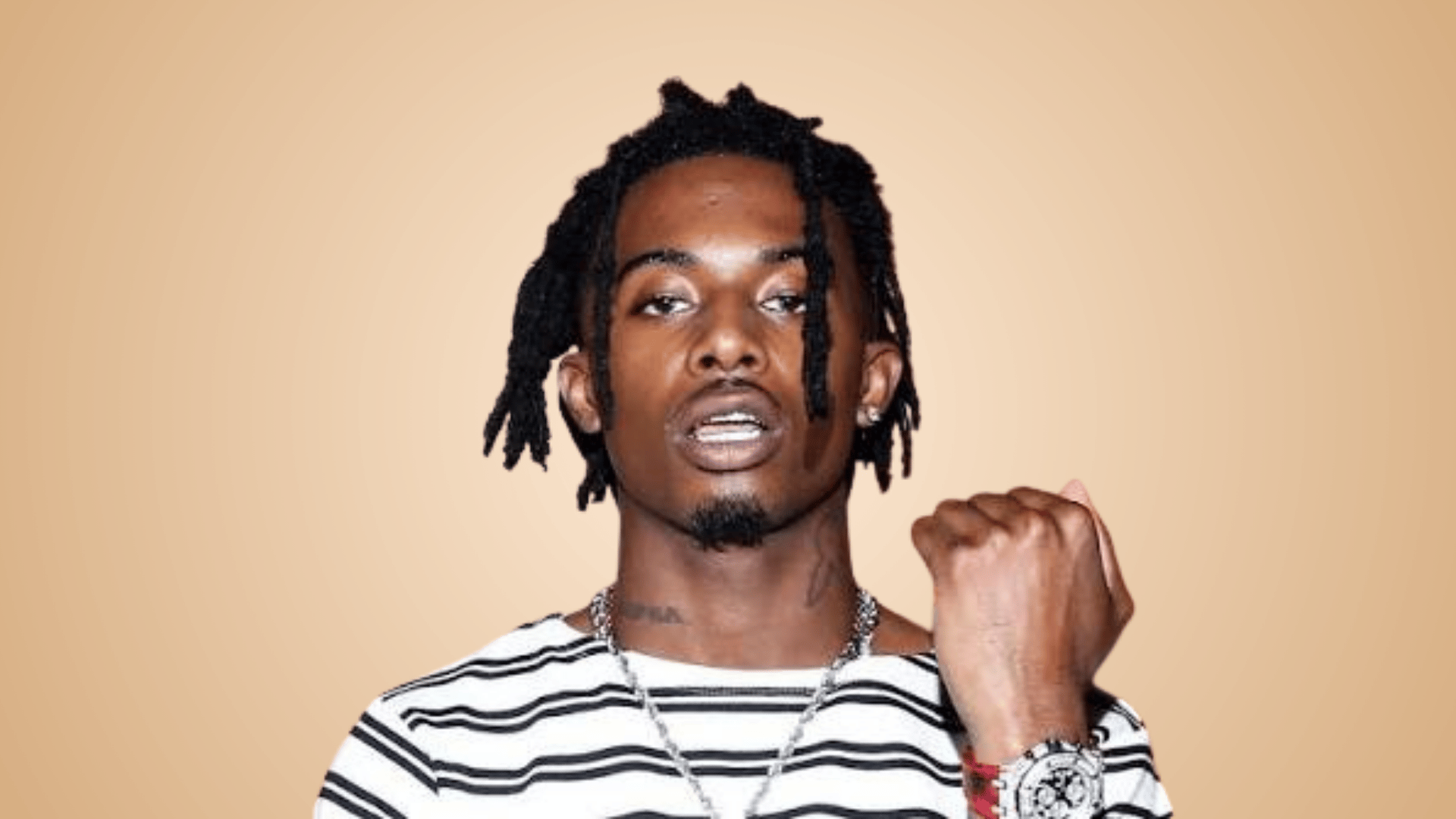 Playboi Carti posing in striped shirt with stylish hairstyle and jewelry