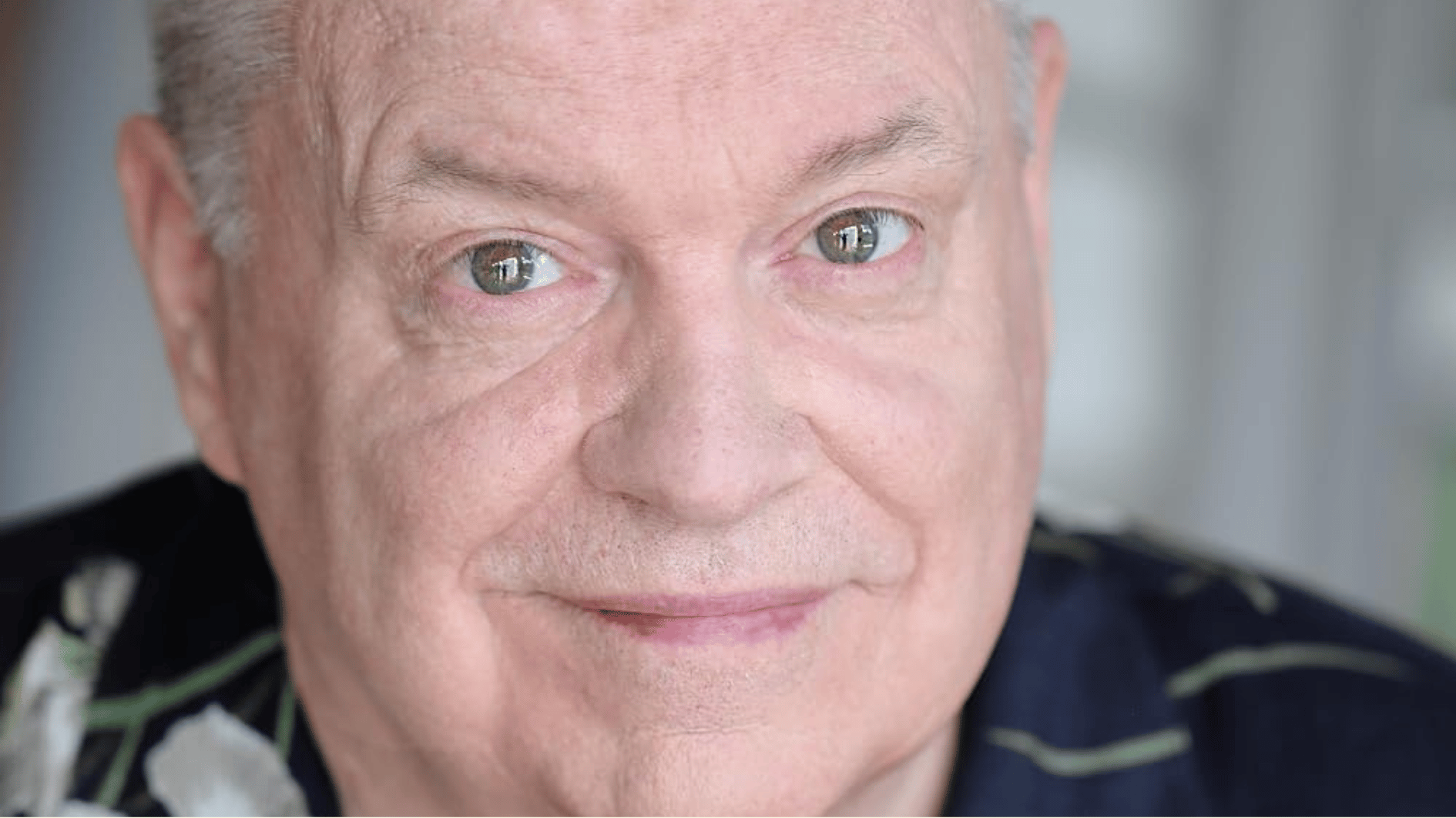 close up portrait of jerry hauk smiling softly at the camera against a blurred background