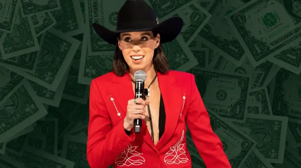 danae hays holding a microphone in a red suit and cowboy hat against a money background