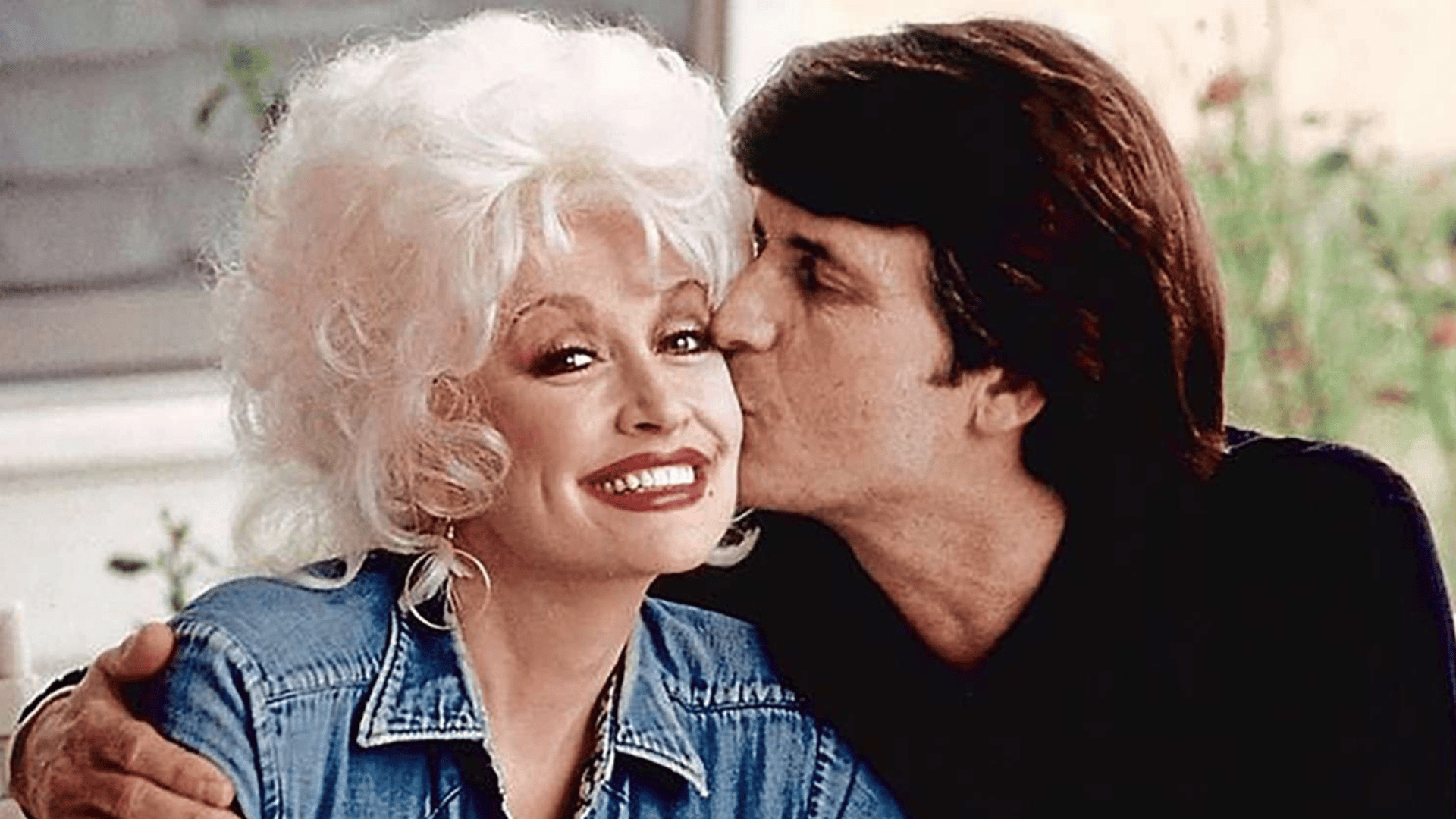 Dolly Parton and Carl Dean sharing a close moment together in a vintage photo.