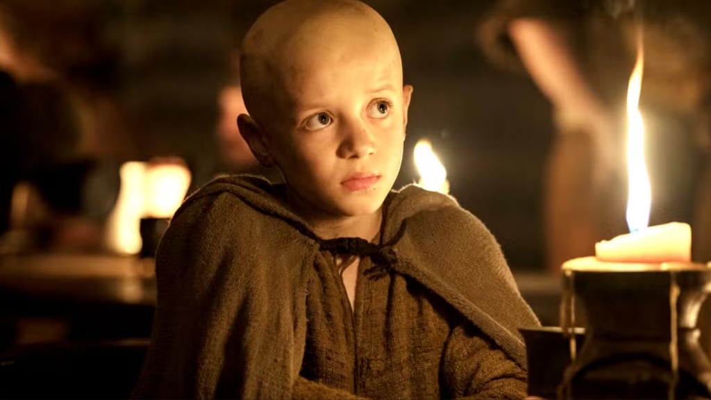 Young Egg, Aegon V Targaryen, sitting indoors beside candlelight in A Knight of the Seven Kingdoms.