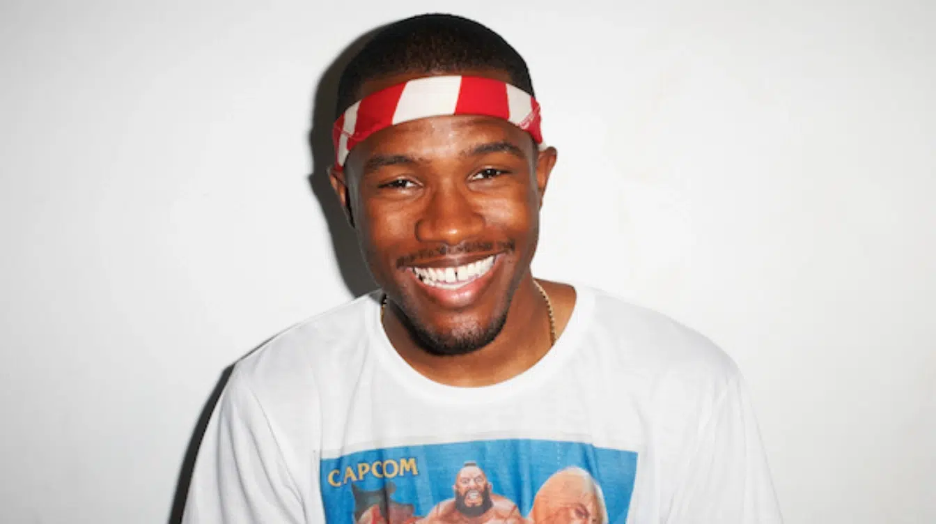 frank ocean smiling while wearing a red and white headband and white graphic shirt