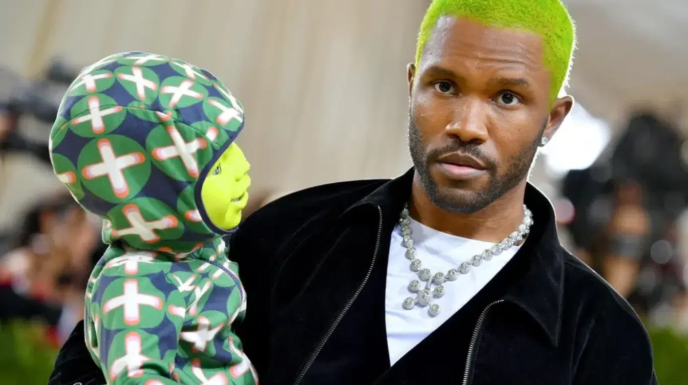 frank ocean with bright green hair holding a colorful doll at a formal event