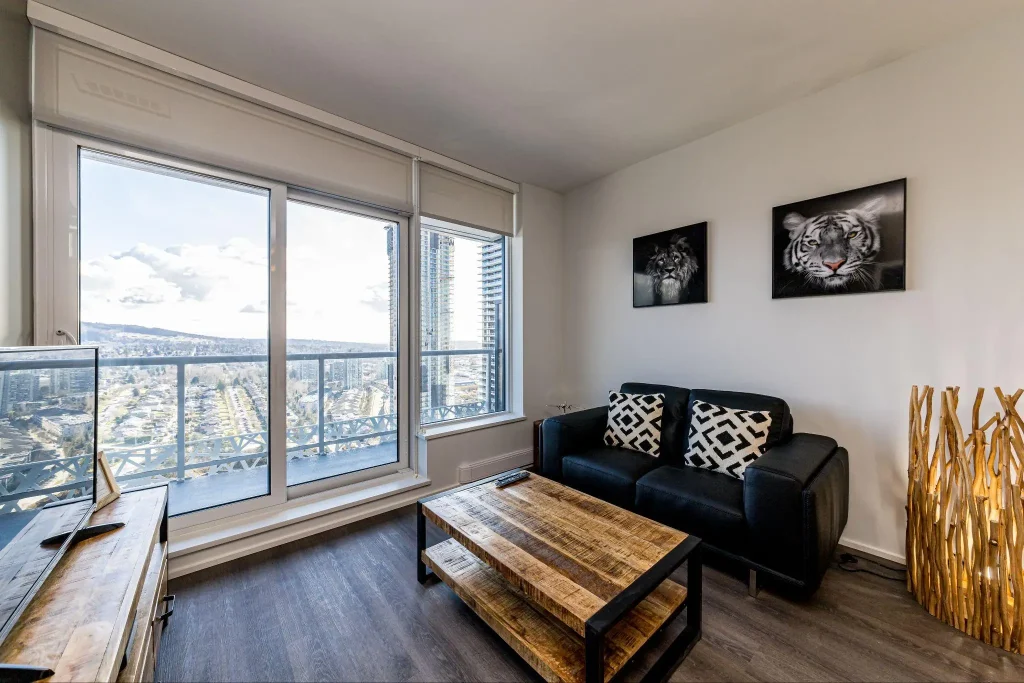 Modern apartment living room with black couch, geometric cushions, and city view through large windows