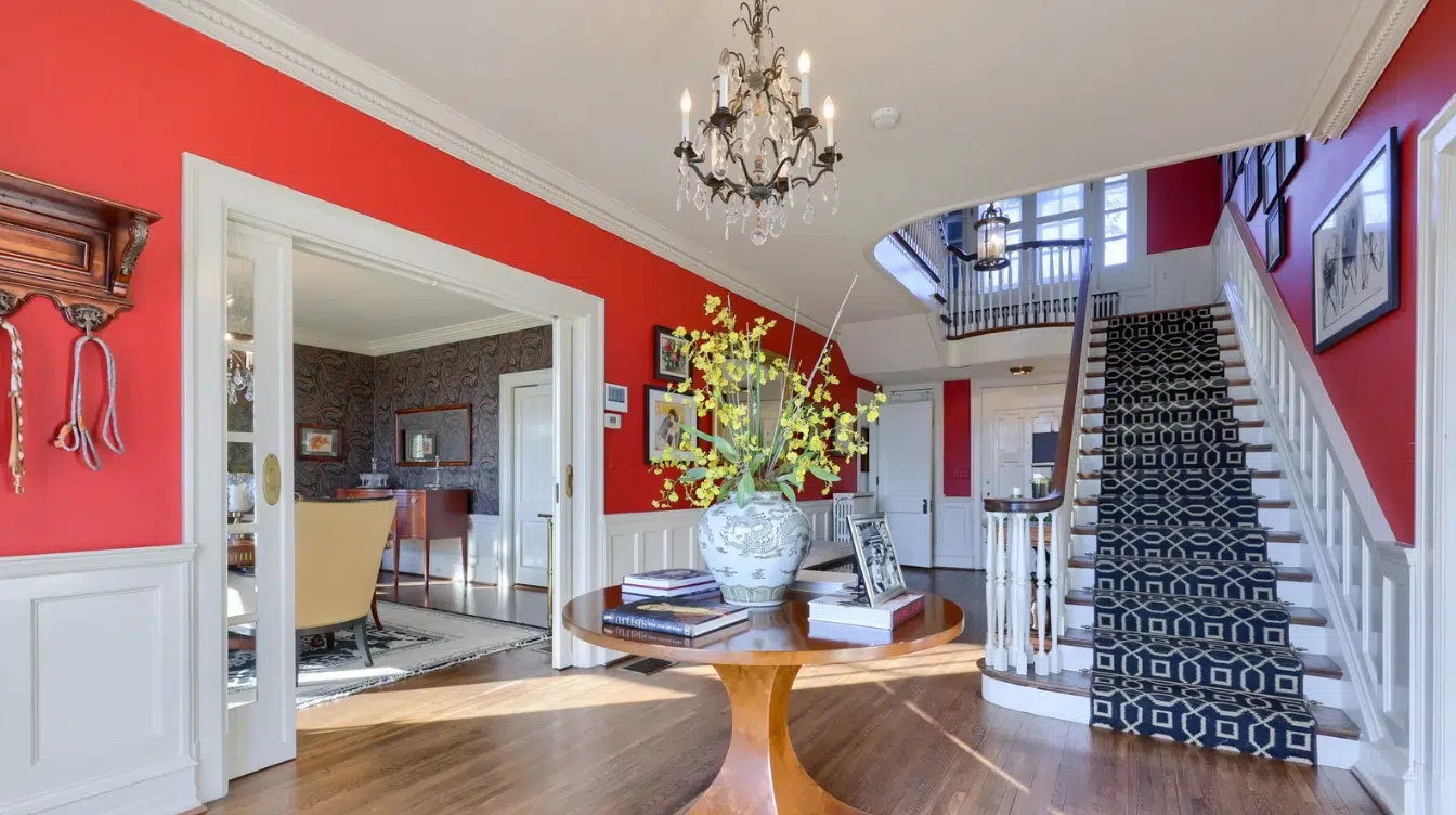 interior foyer of taylor swifts wyomissing childhood home with red walls chandelier staircase and round wooden table