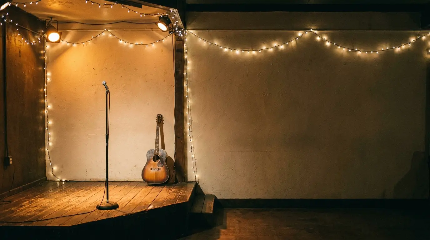 Microphone and guitar on dimly lit stage with string lights in intimate venue