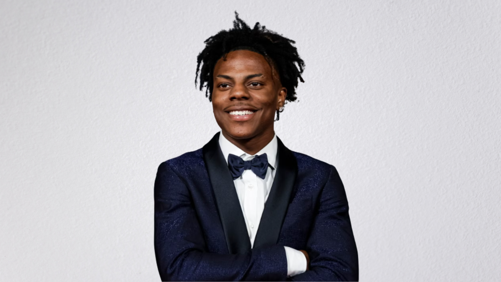 IShowSpeed wearing a black suit and white shirt against a dark background.