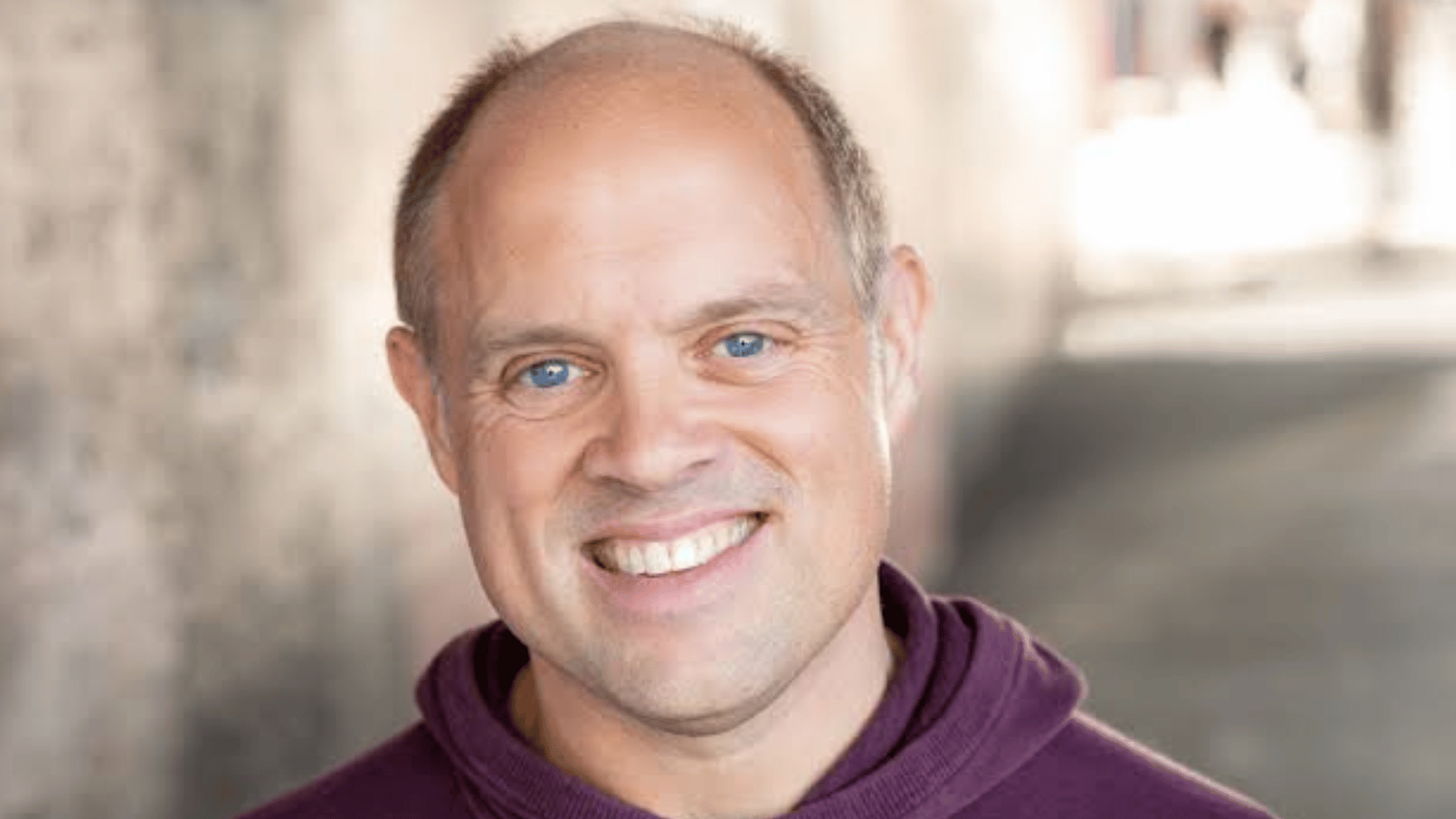 jim woods in a purple hoodie posing for a portrait against a softly blurred indoor background