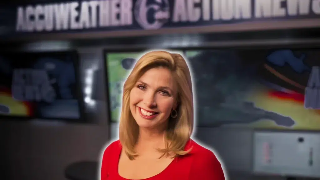 karen rogers smiling in a red dress with a blurred weather studio background and television screens