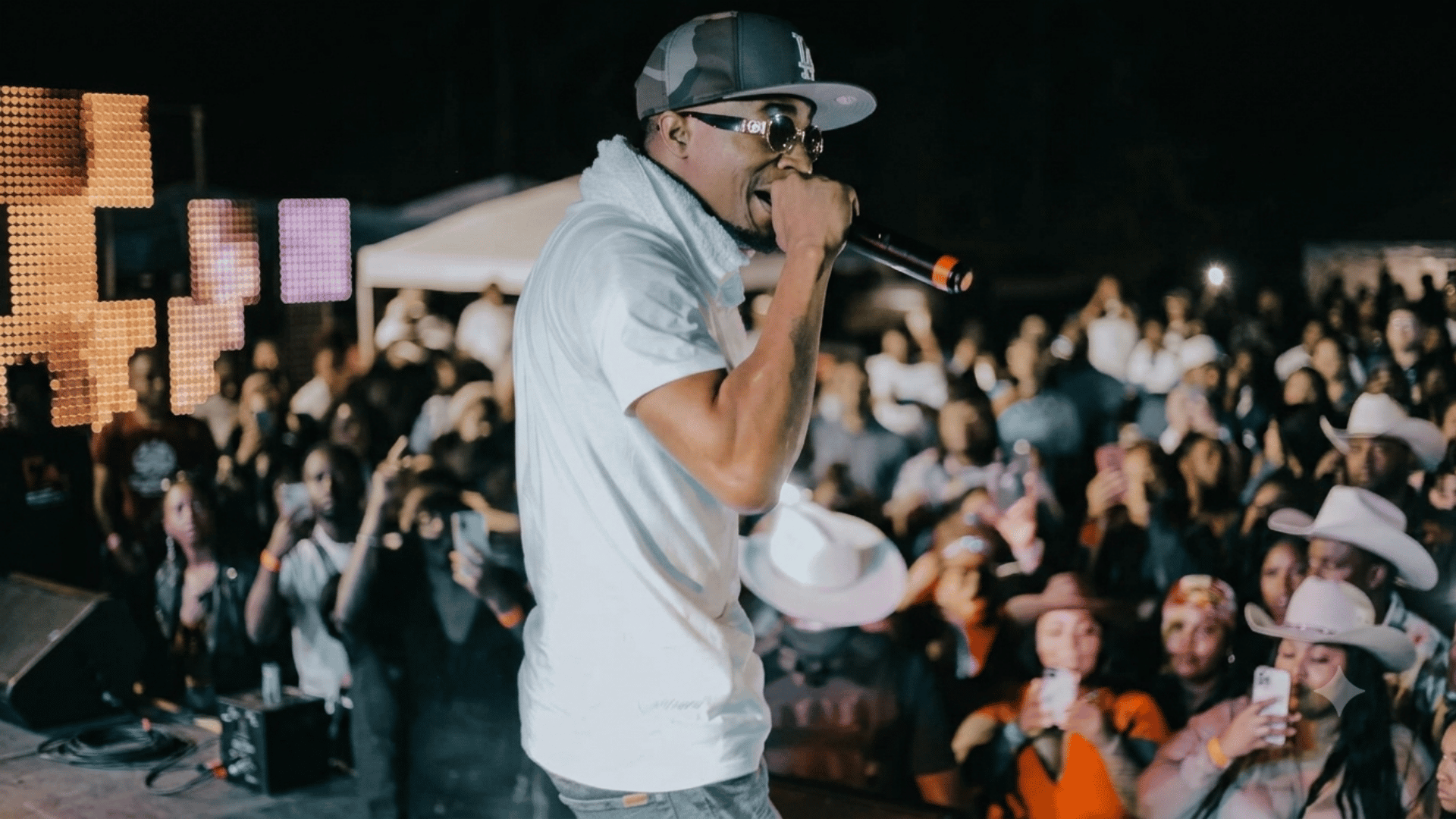 King George performing live on stage with a microphone in front of a large audience at a concert.